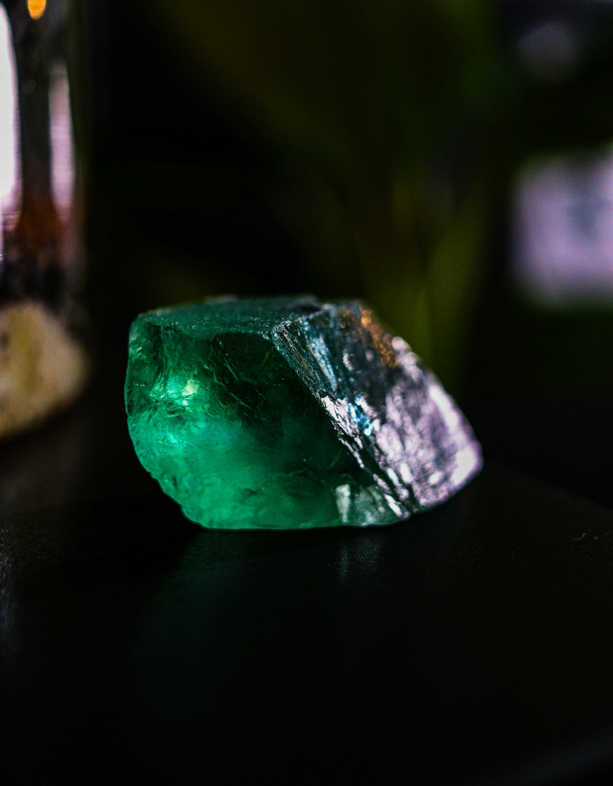 A rough, uncut emerald gemstone with vibrant green hues