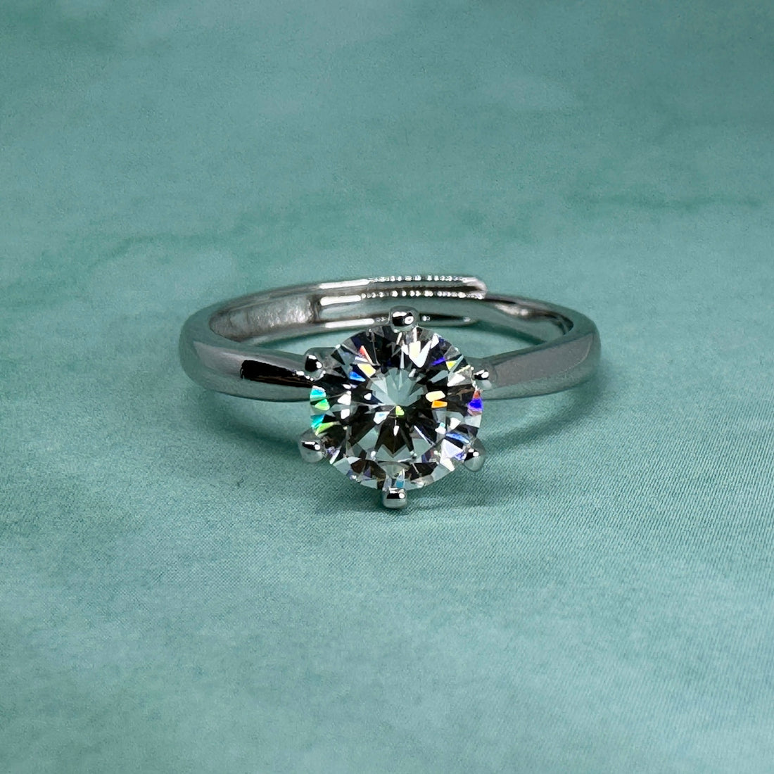 A diamond engagement ring on a teal background