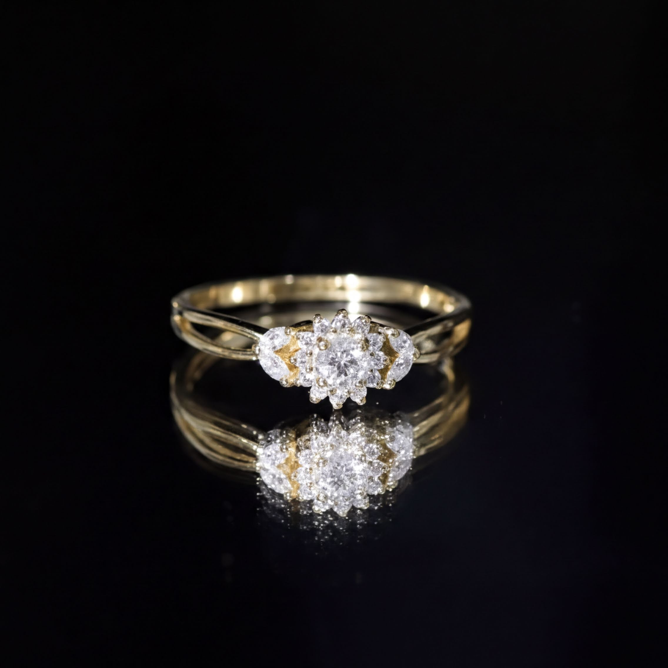 A gold ring with a large central diamond surrounded by smaller diamonds, set against a black background.