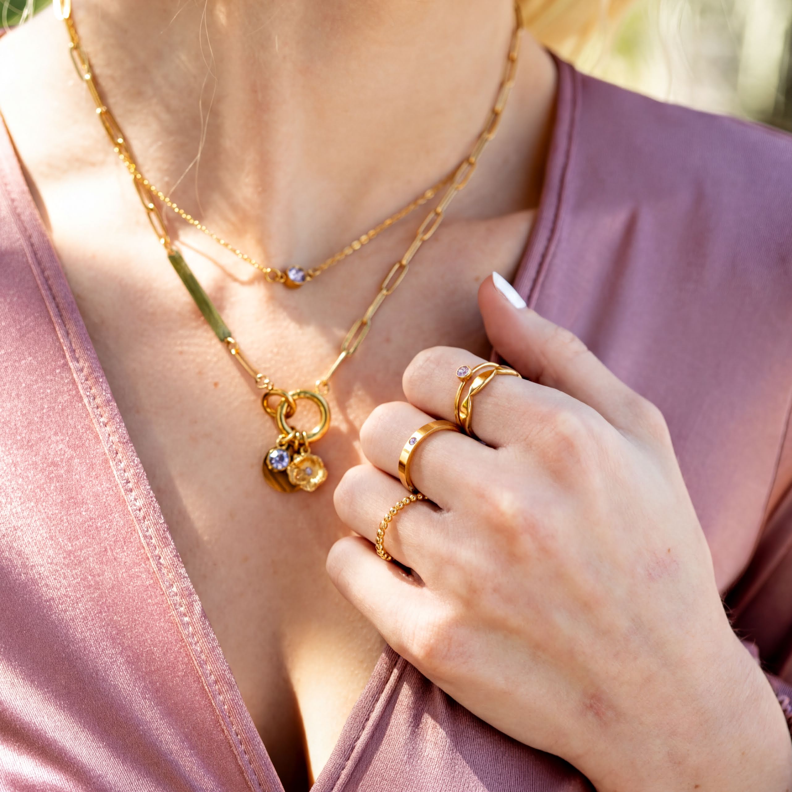 A close-up view of a person's hand wearing multiple rings and a necklace.