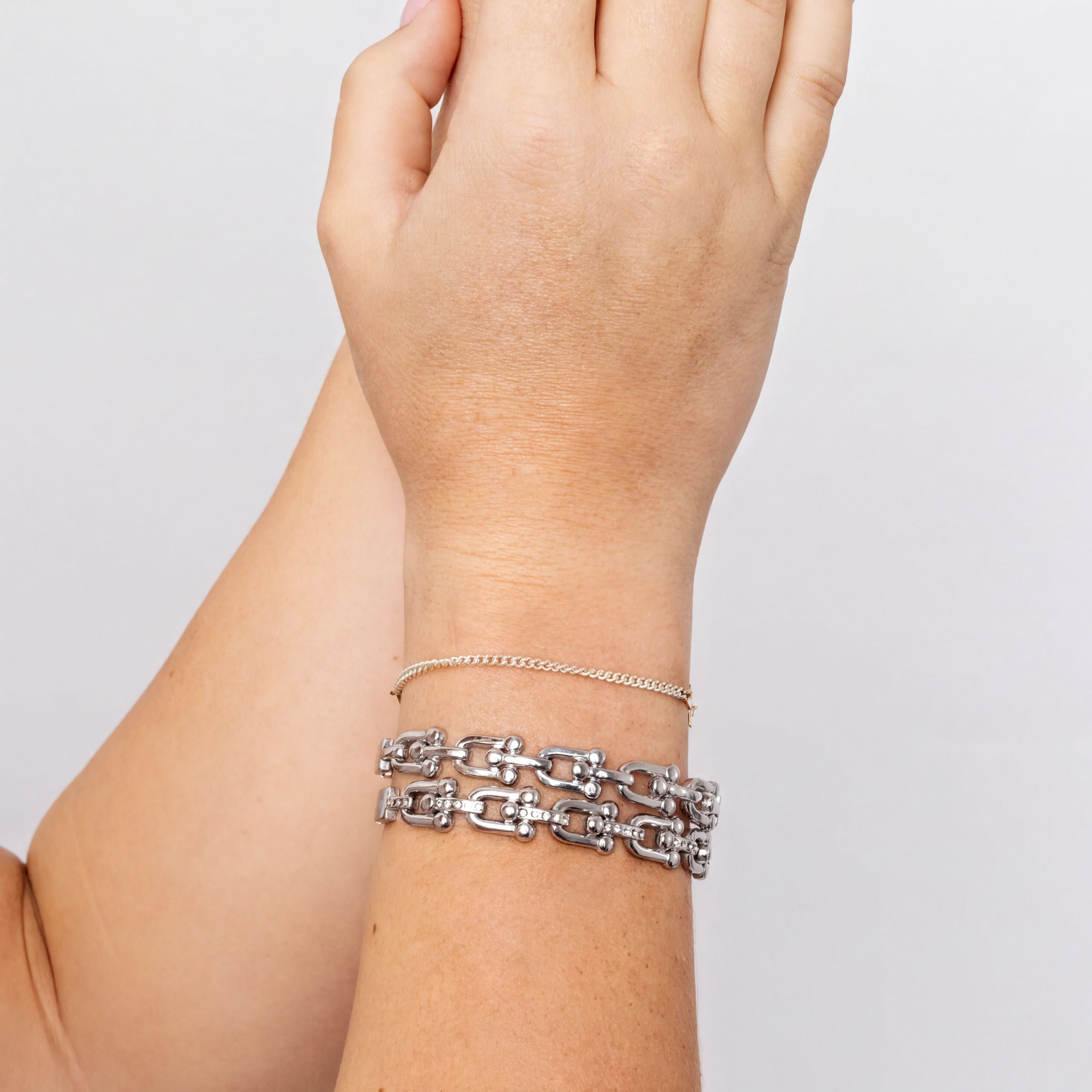Silver bracelet on a wrist against a plain background