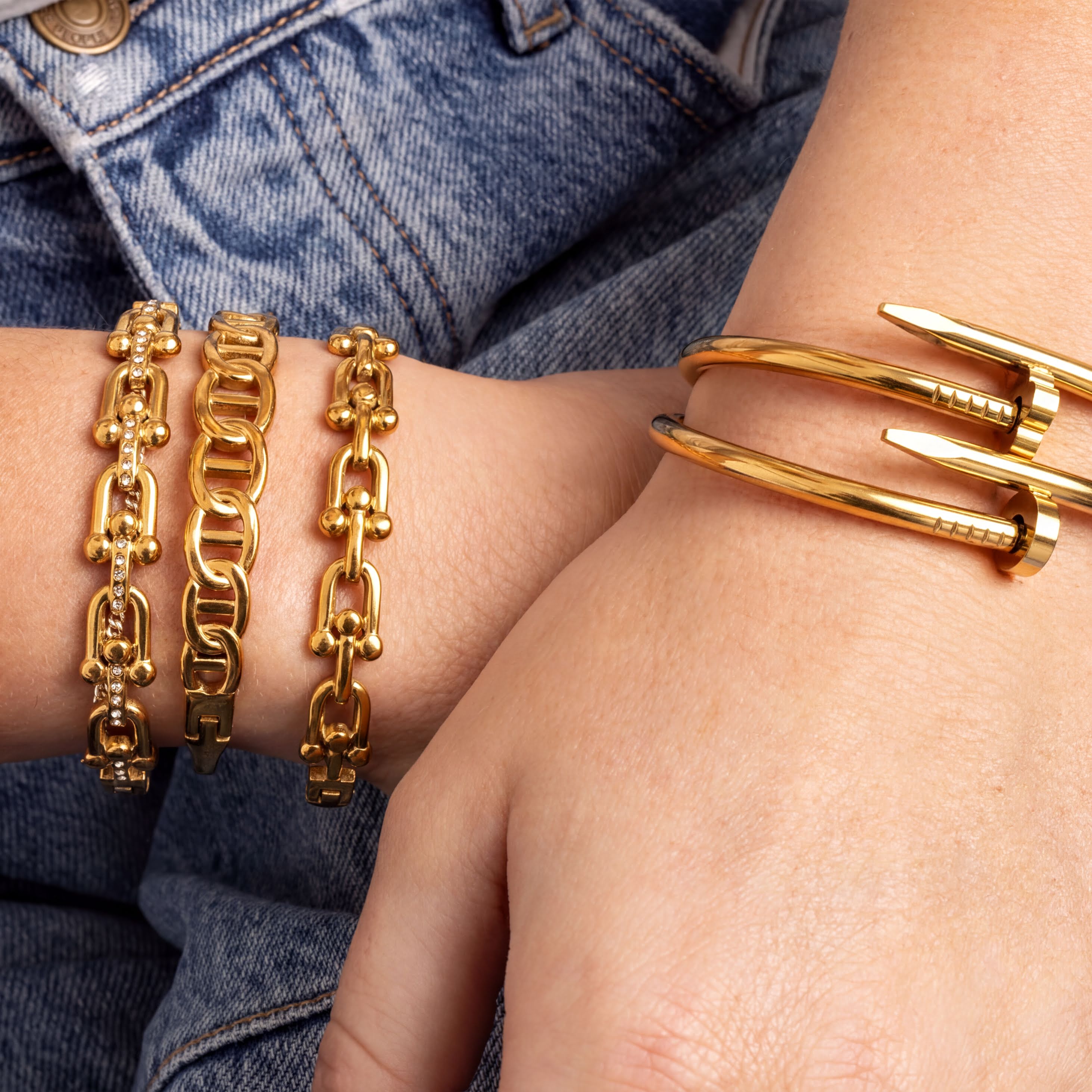 Gold bracelets on a person's wrist with denim background