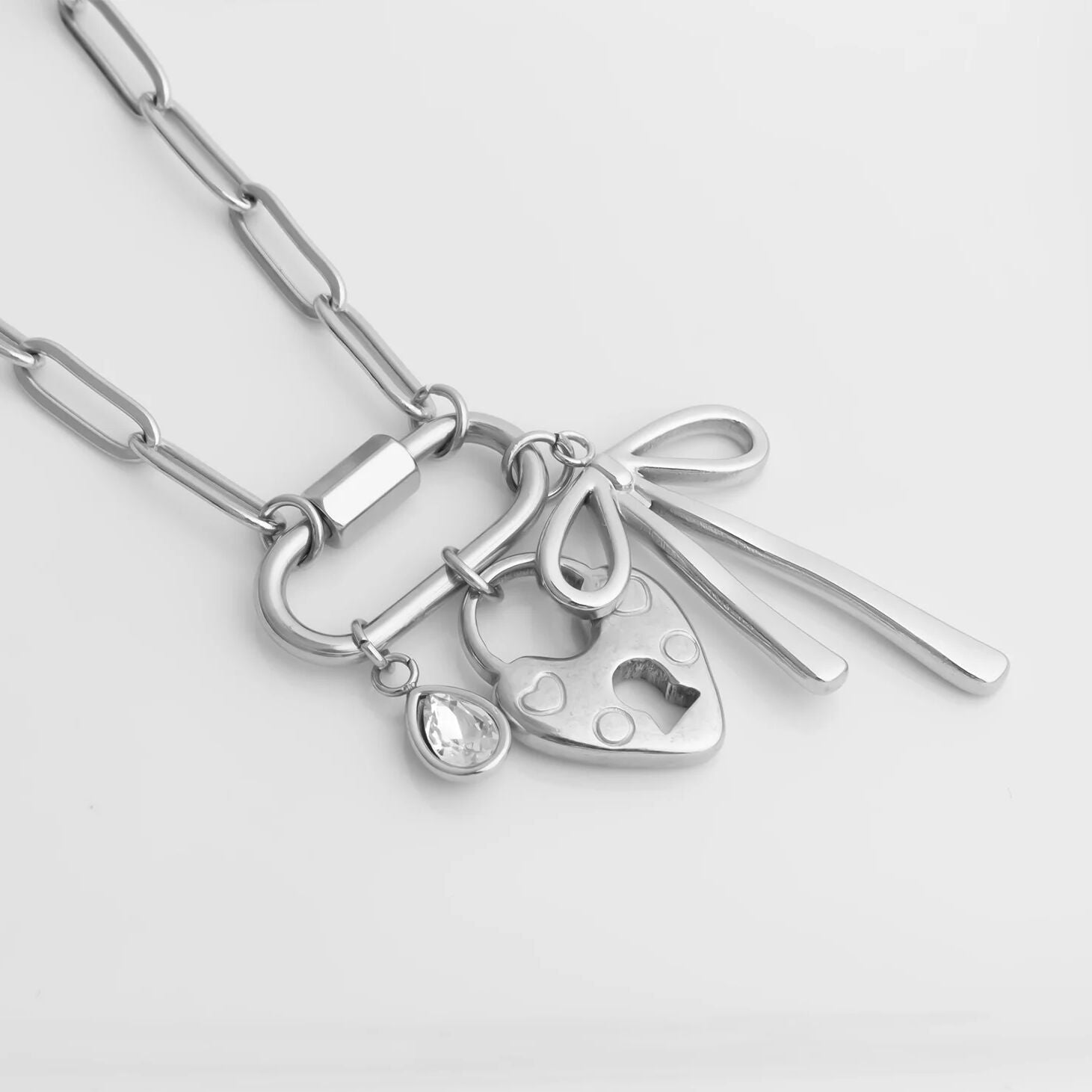 Silver necklace with various charms on a light gray background