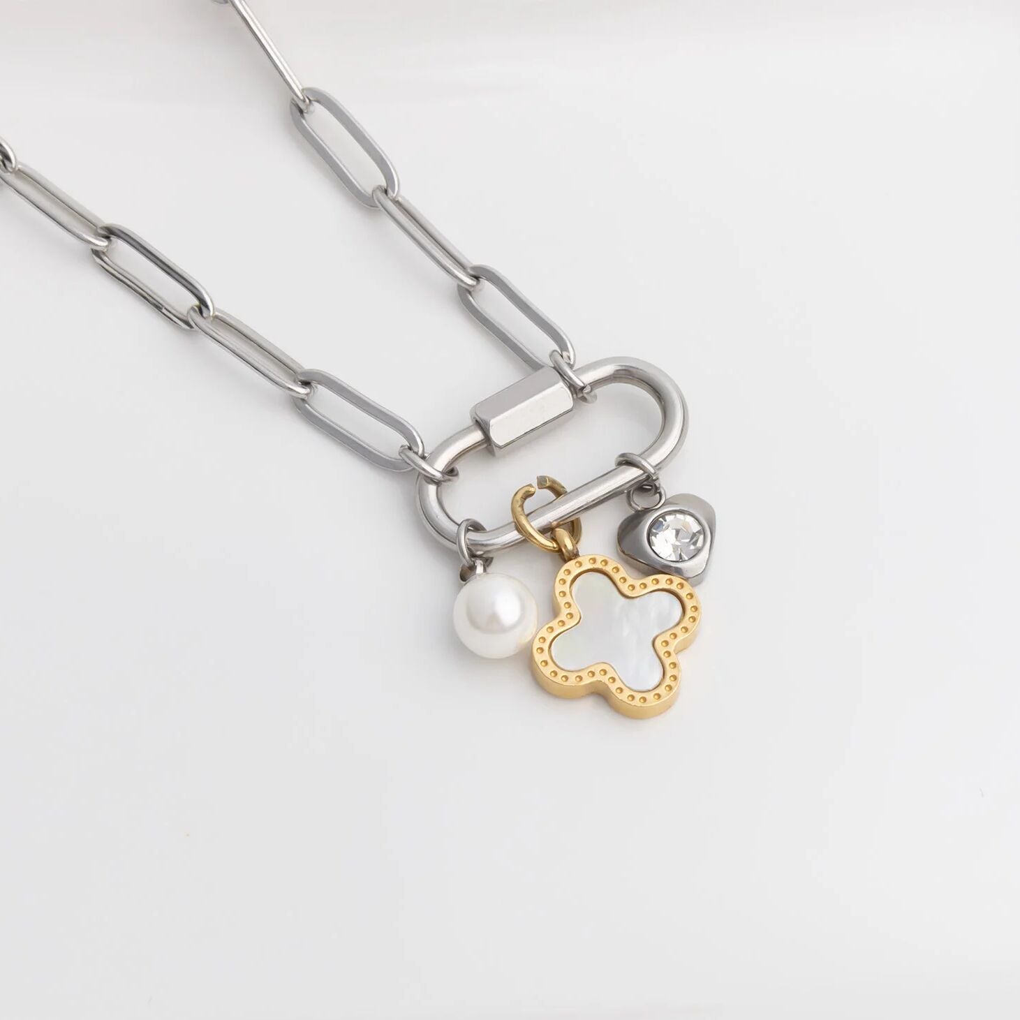 Silver chain necklace with a lock and flower-shaped charm on a white background