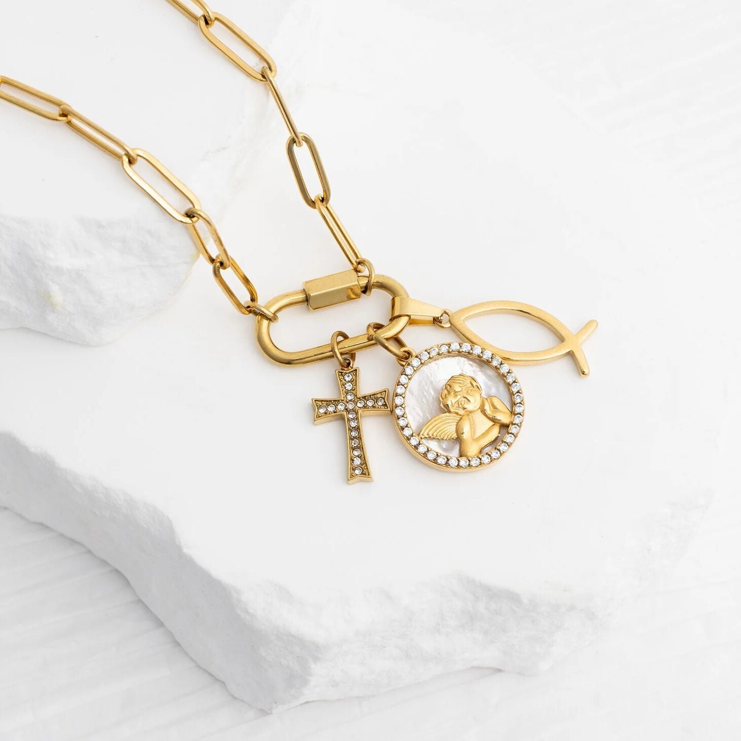 Gold necklace with charms on a white marble surface