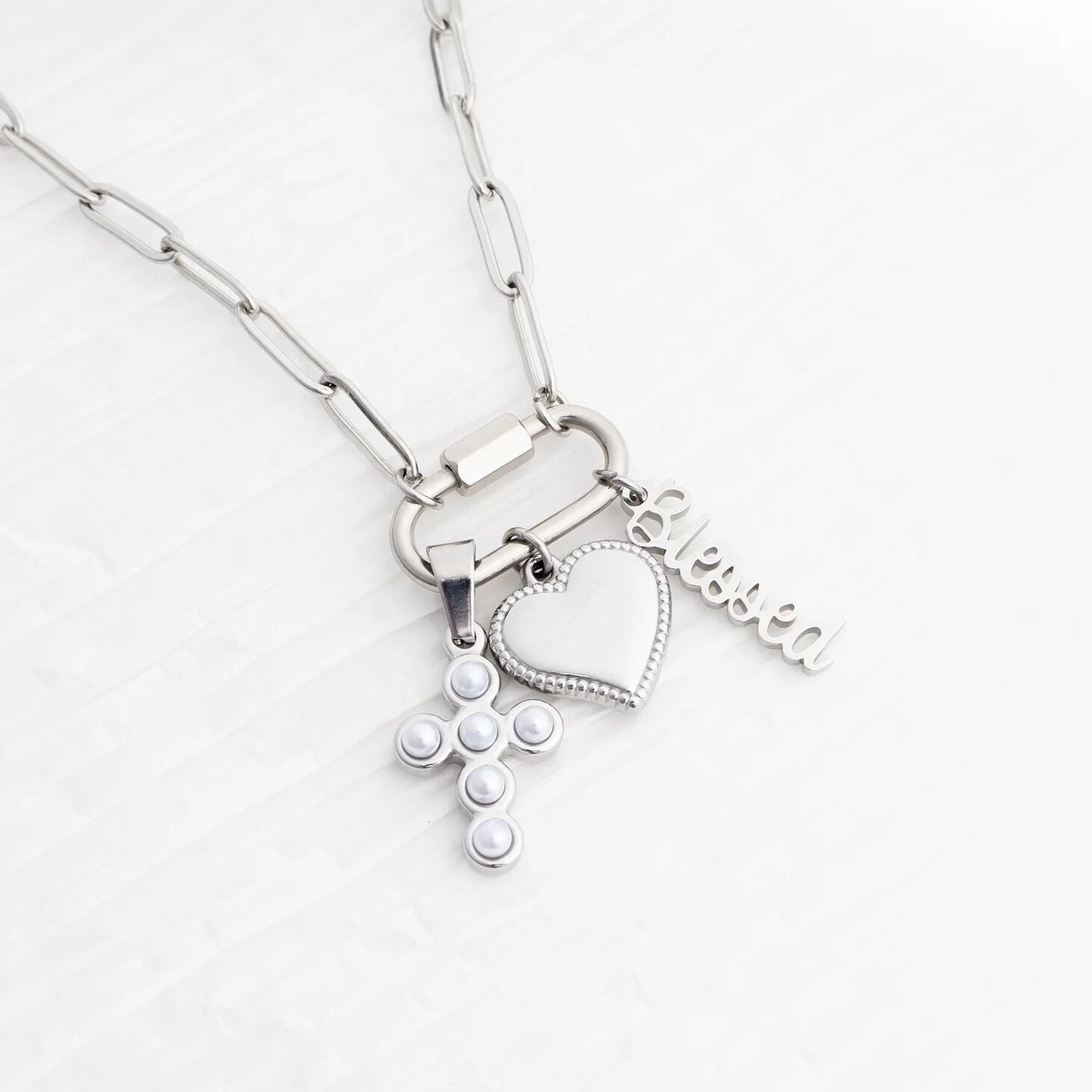 Silver necklace with heart-shaped pendant and 'Eloise' tag on a white background