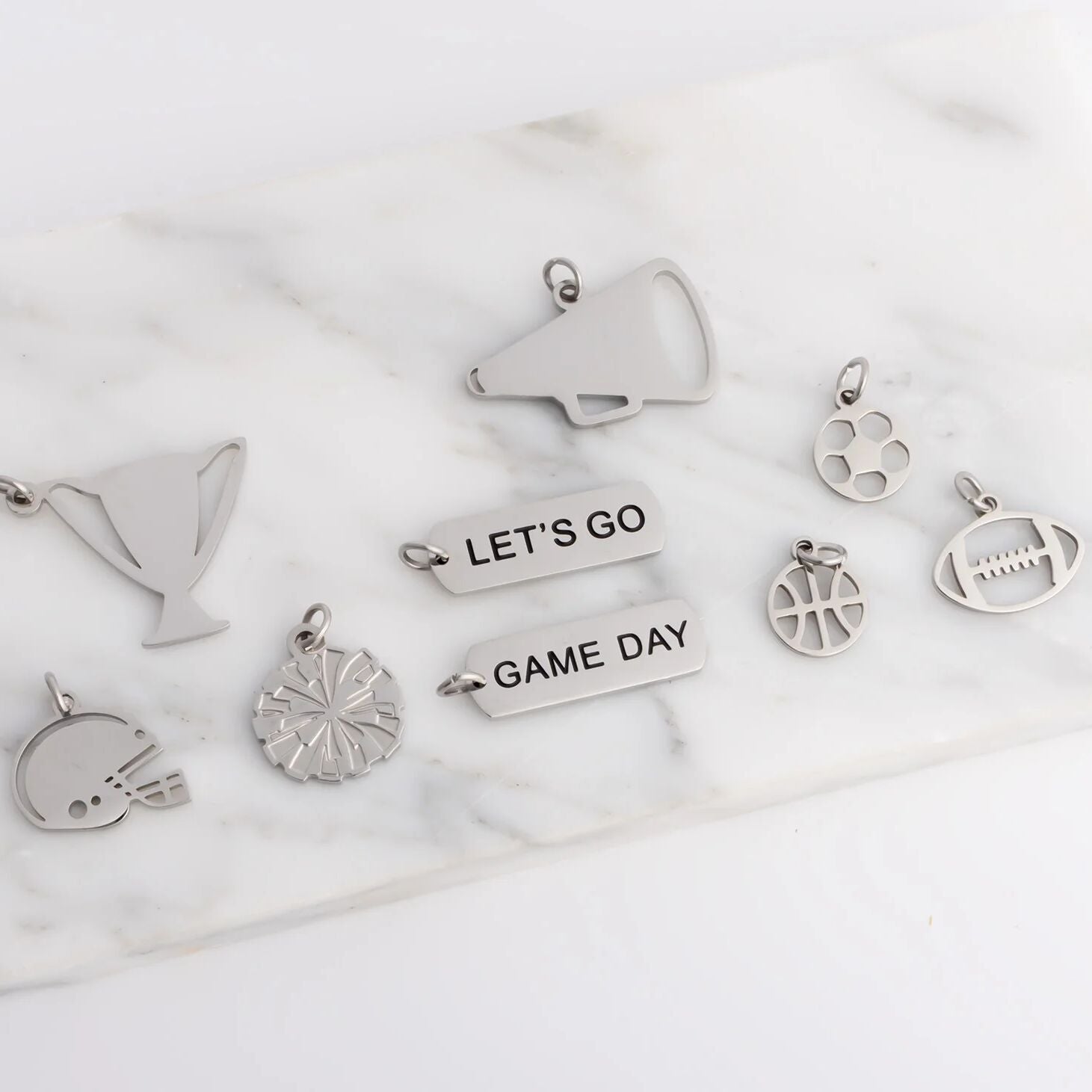 Collection of silver charms on a marble surface
