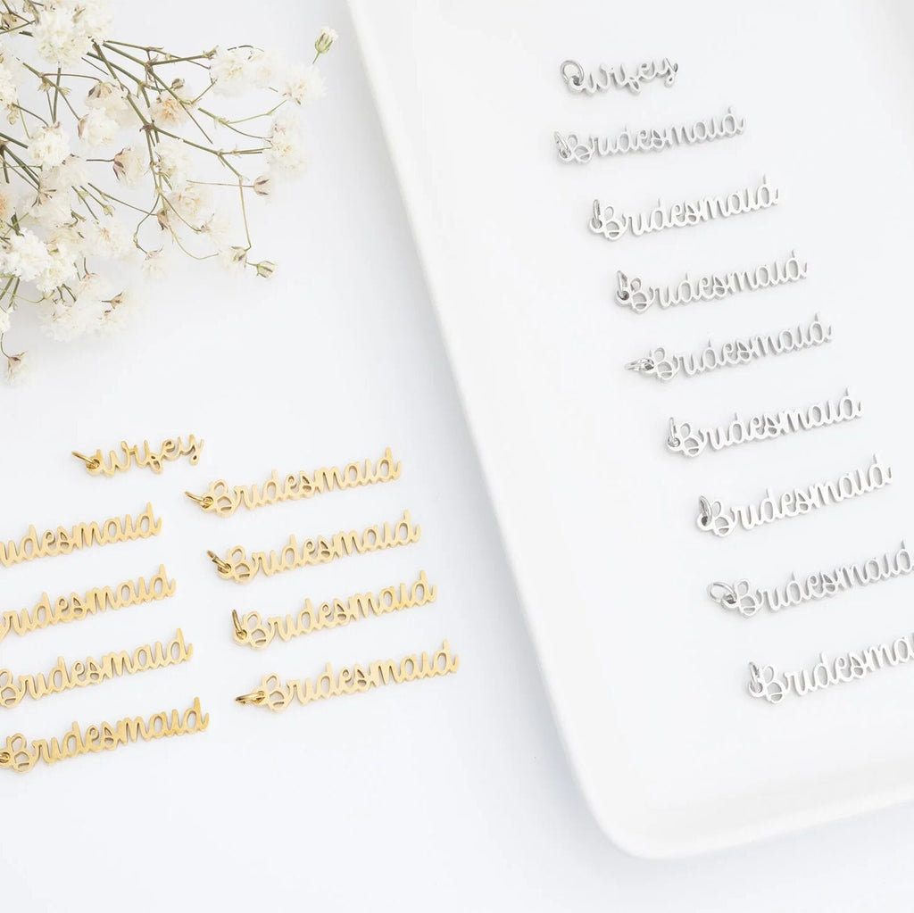 Gold 'Bridesmaid' pins on a white surface with baby's breath flowers.