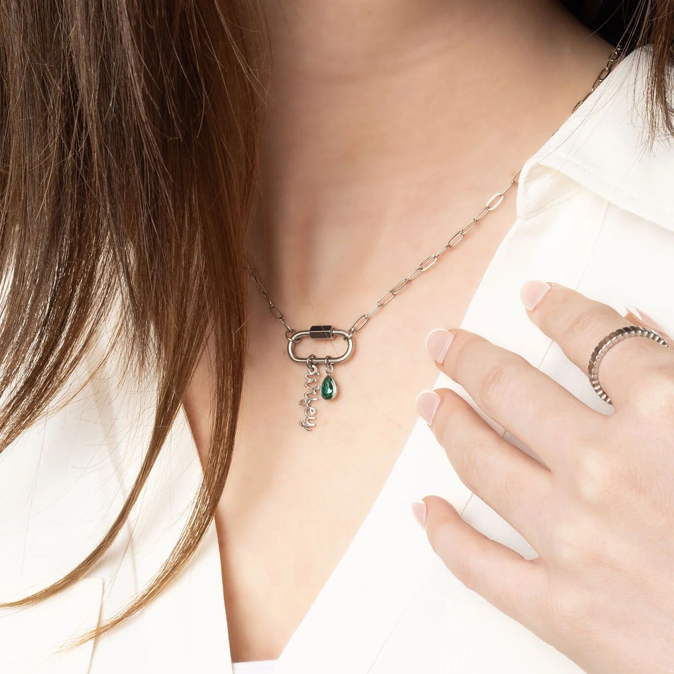 Necklace with a pendant worn by a person, with a hand touching the necklace.