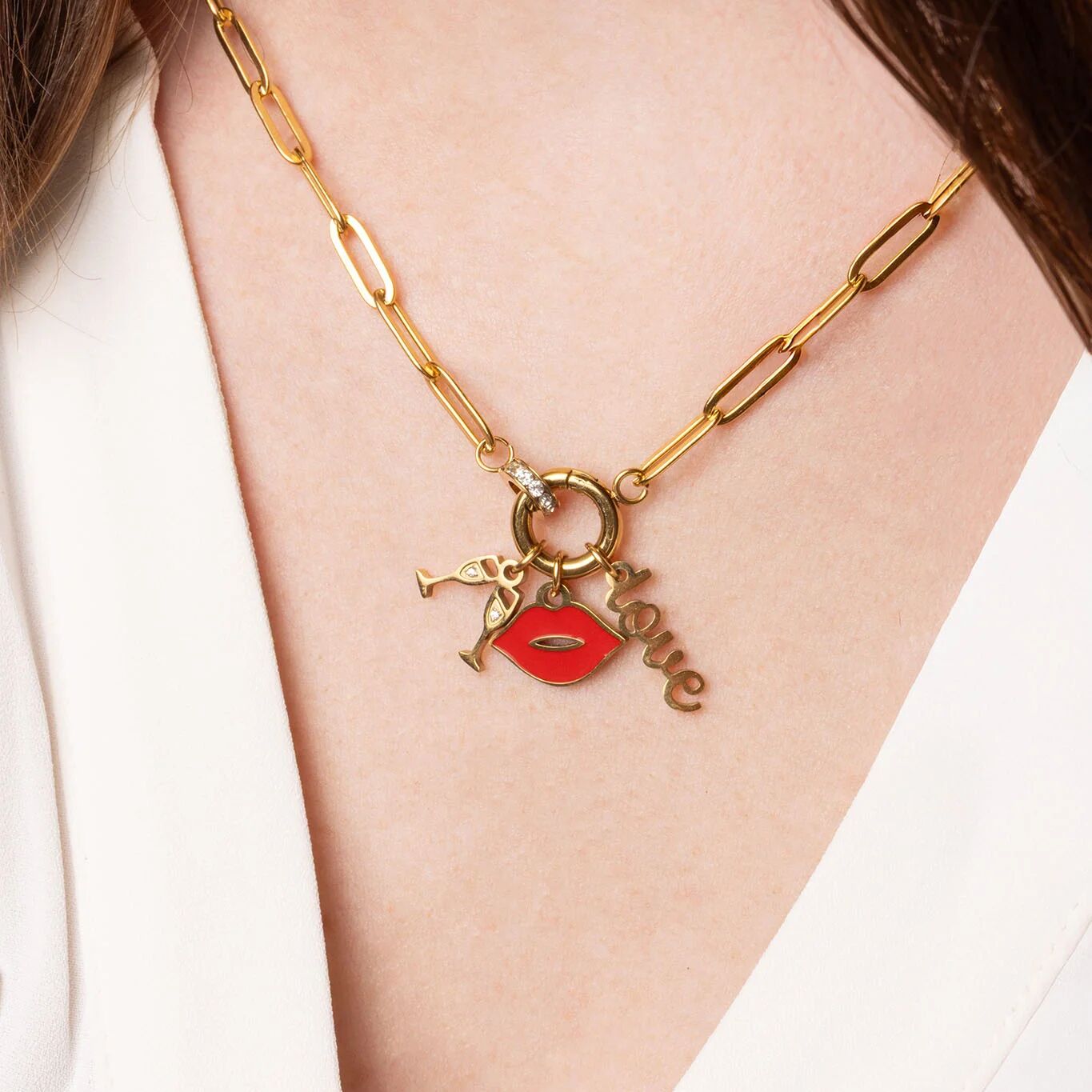 Gold necklace with charms on a person wearing a white top