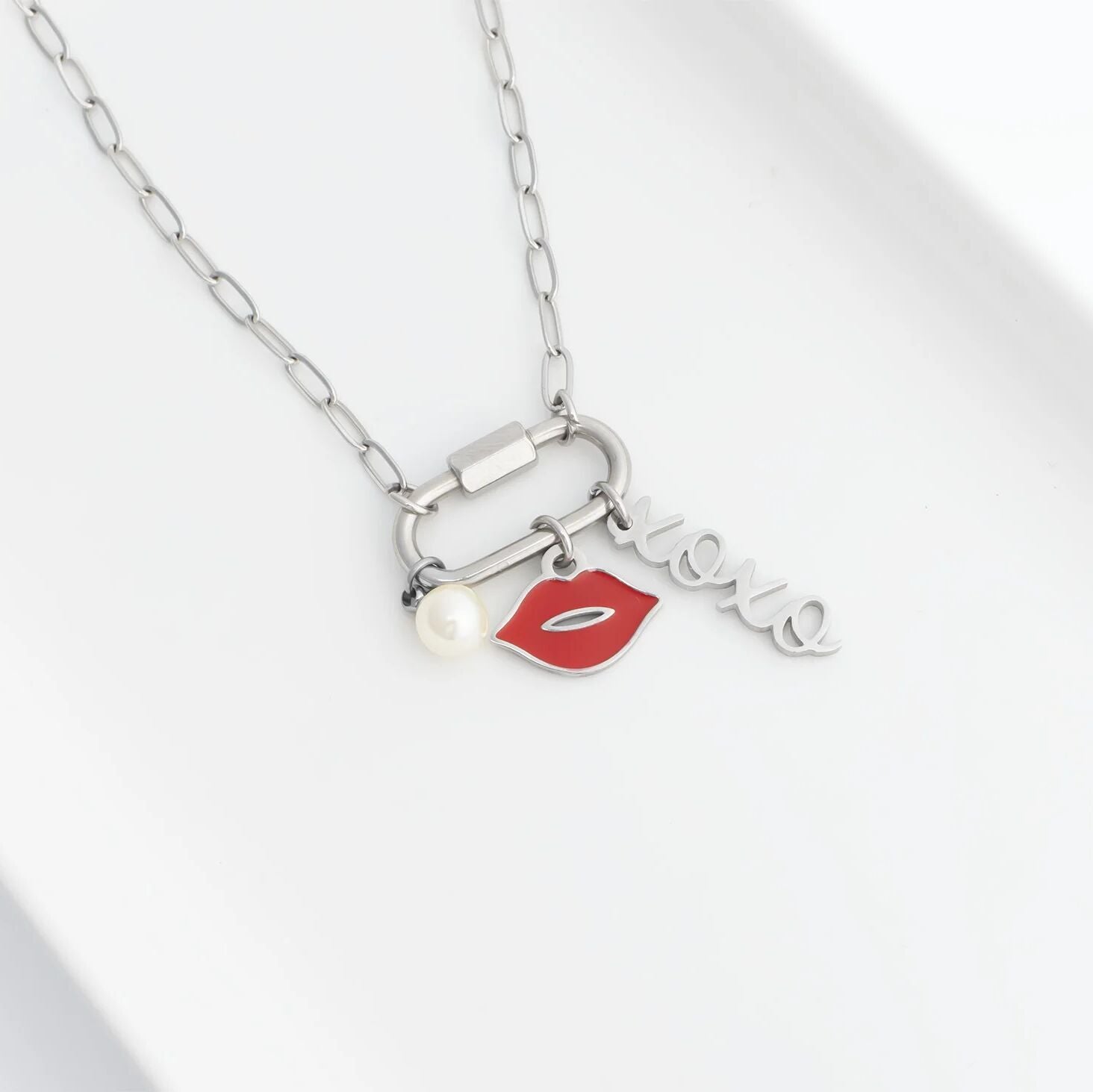 Necklace with lip-shaped charm, pearl, and 'love' pendant on a white background