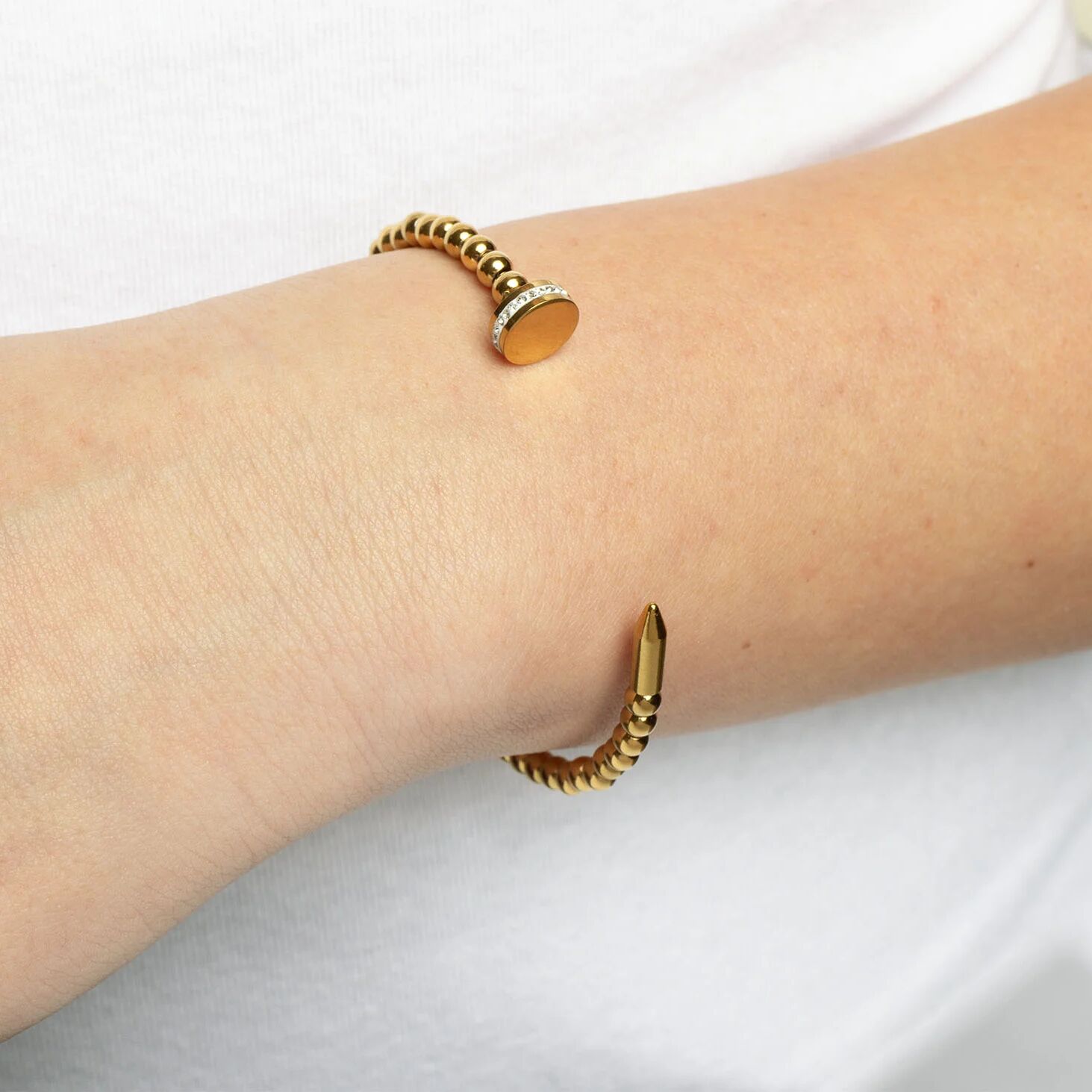Gold bracelet on a wrist with a plain background