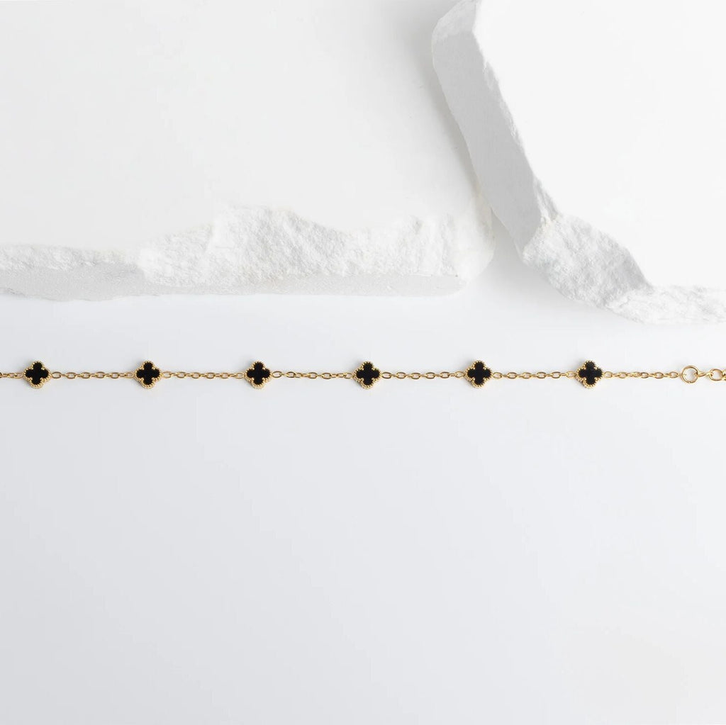 Gold Small Floral Motif Bracelet  with black clover-shaped charms on a white background