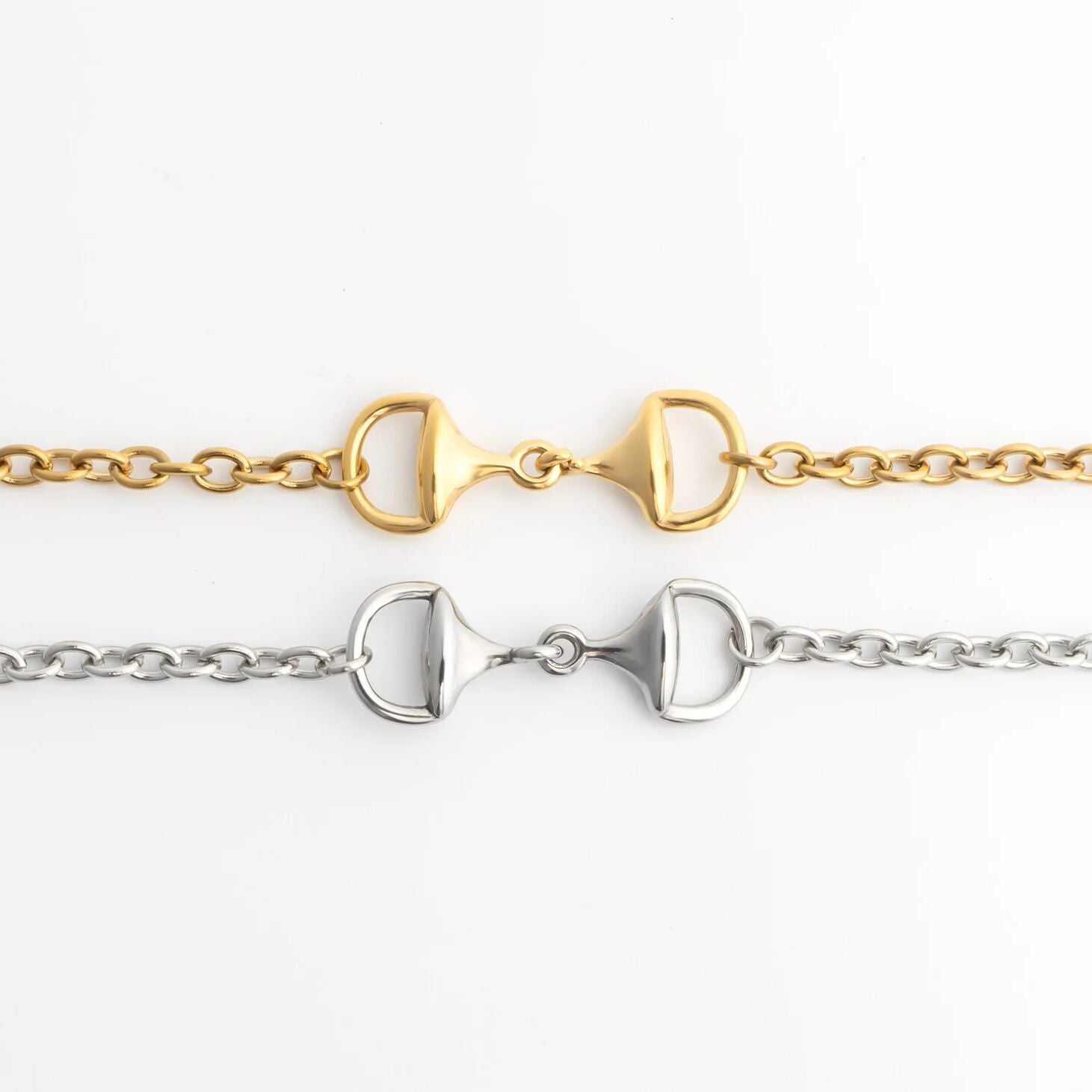 Two gold and silver horse bit bracelets on a white background