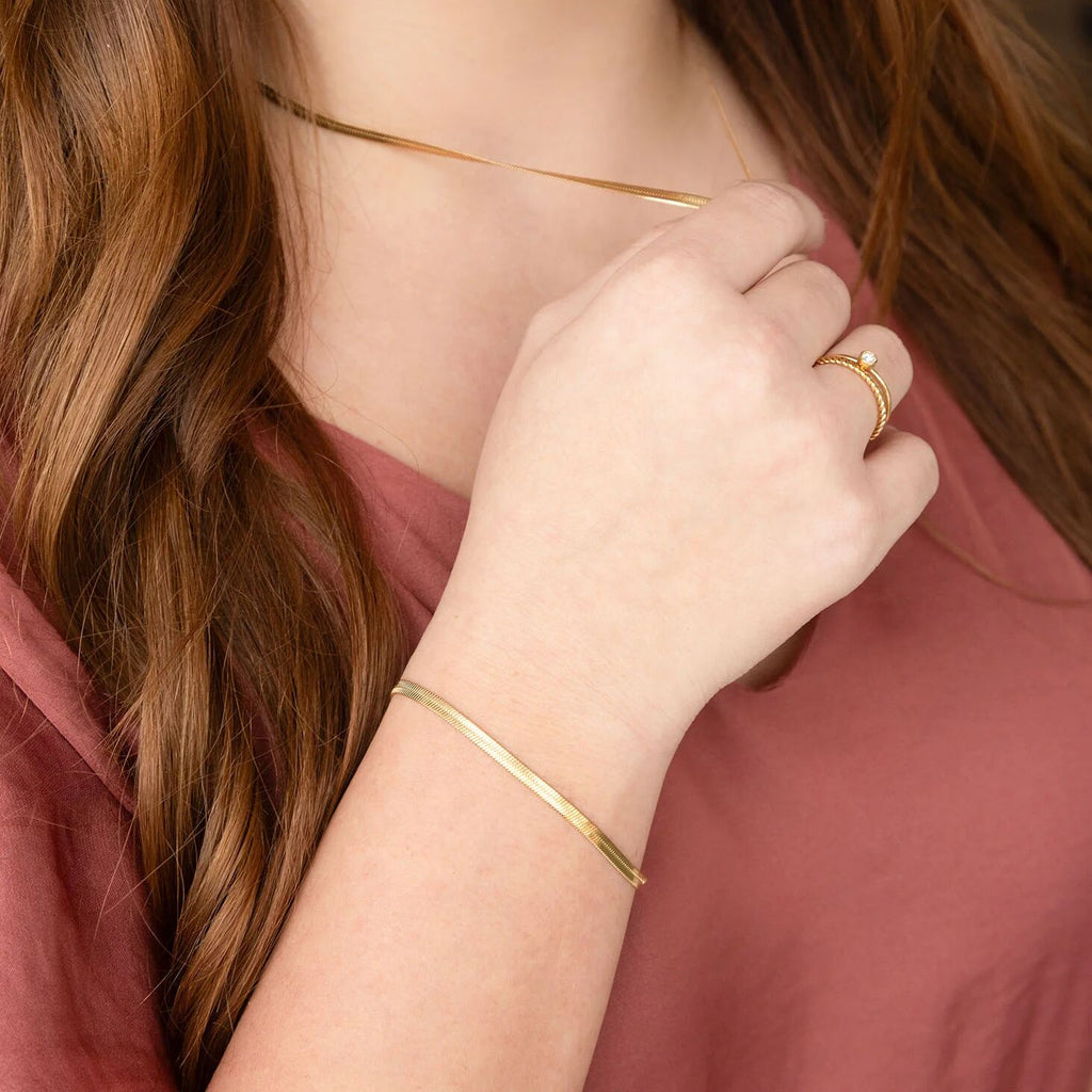 Close-up of a person wearing gold jewelry including a necklace, bracelet, and ring.