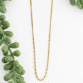 Gold necklace on a white background with green leaves