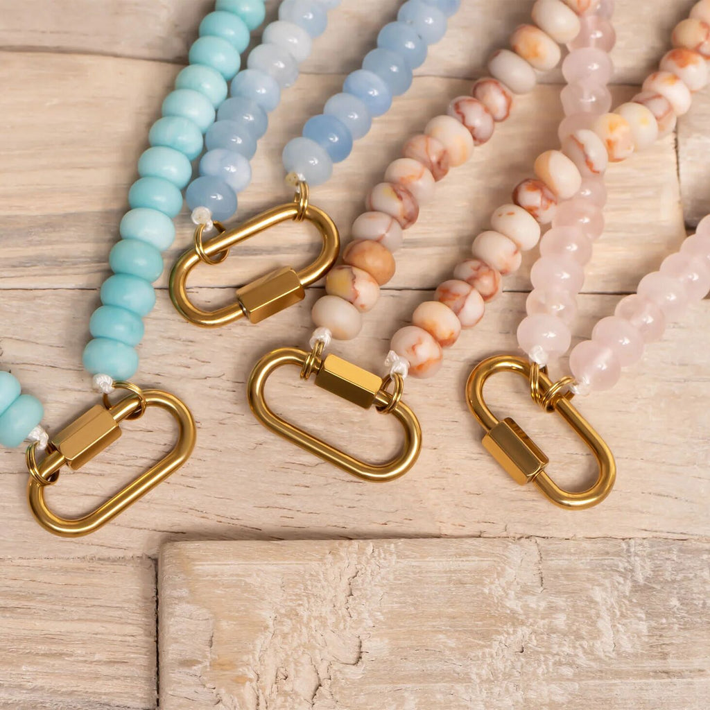 Beaded necklaces with gold clasps on a wooden surface