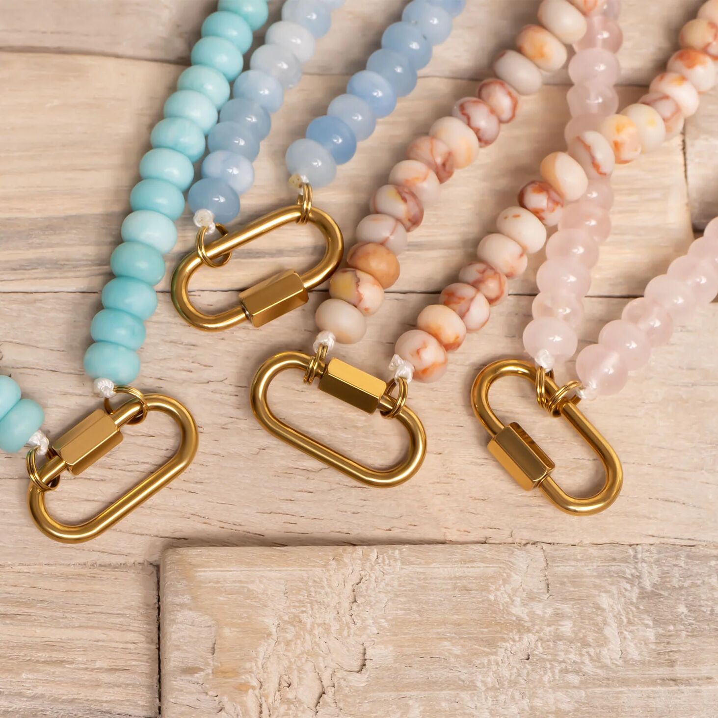 Beaded necklaces with gold clasps on a wooden surface