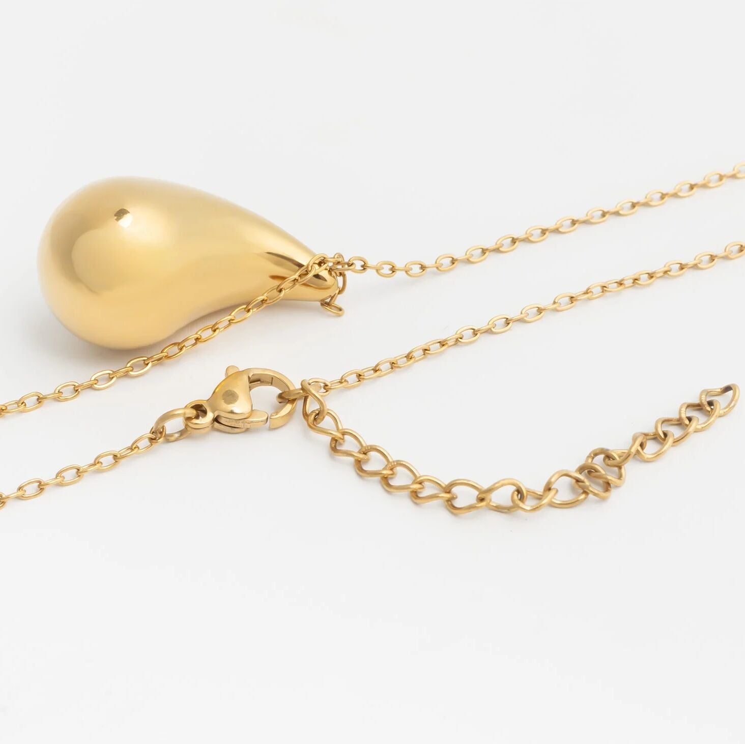 Gold necklace with a teardrop-shaped pendant on a white background