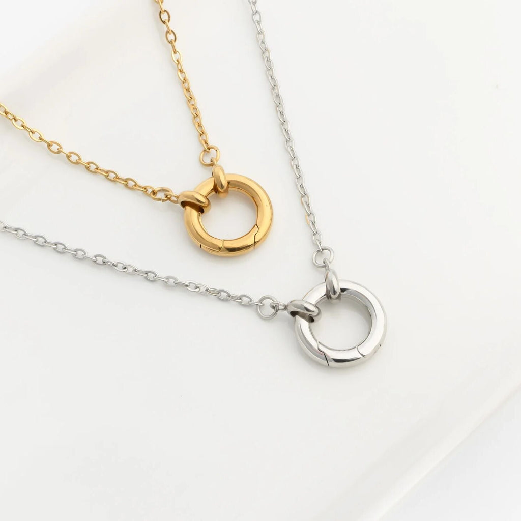 Two necklaces with circular pendants, one gold and one silver, on a light background.