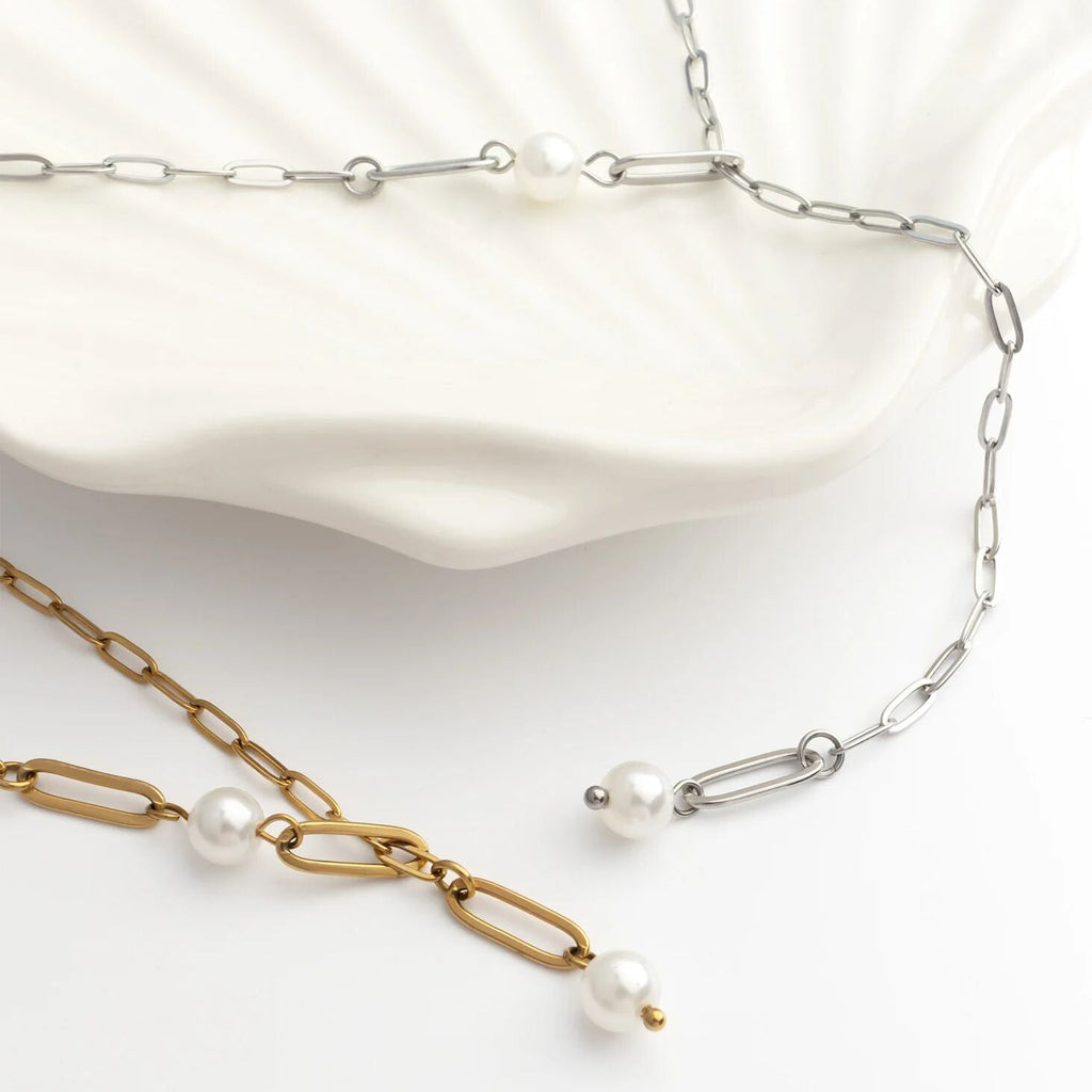 Two pearl necklaces, one gold and one silver, on a white background.