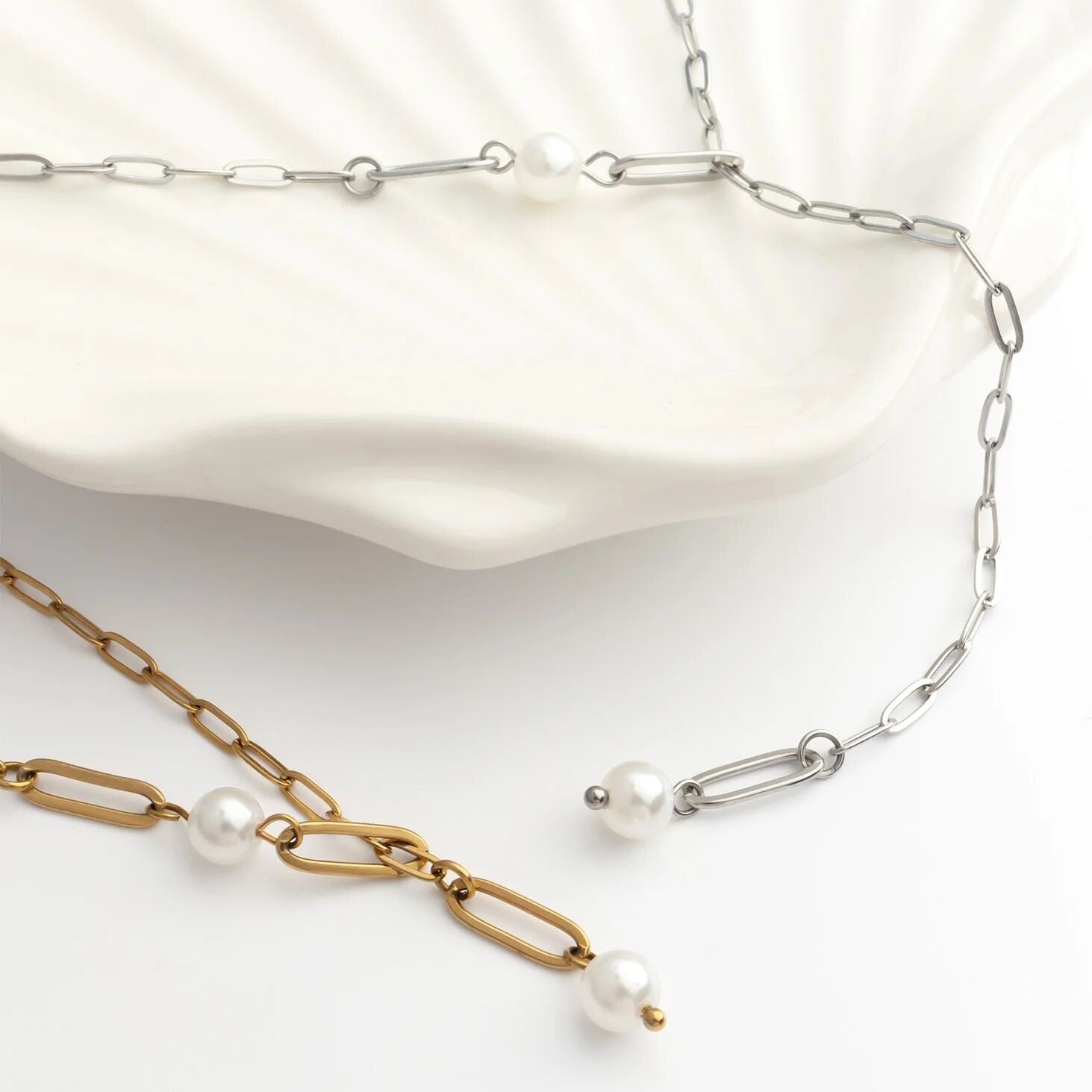 Two pearl necklaces, one gold and one silver, on a white background.