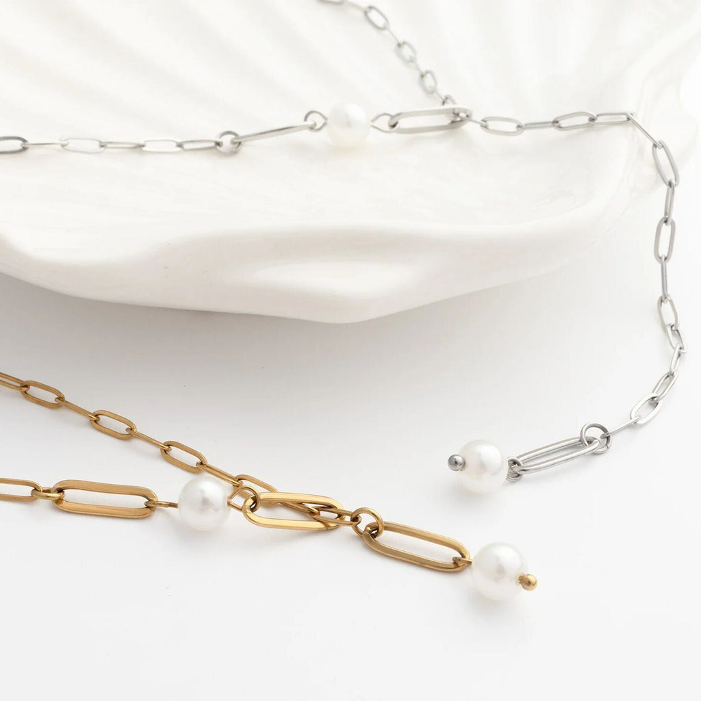 Two necklaces, one gold and one silver, with pearl accents on a white background.