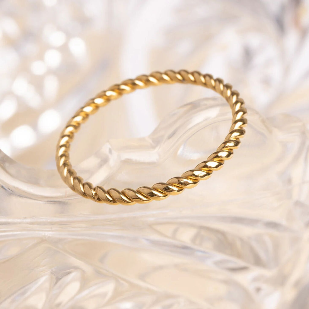 Gold ring with a textured design on a soft, blurred background