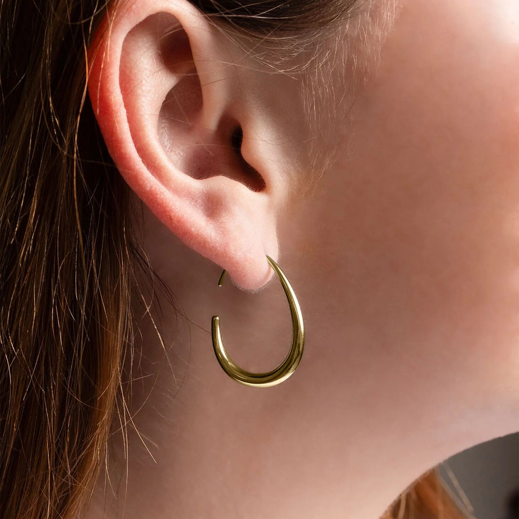 Gold hoop earring worn by a person with brown hair.