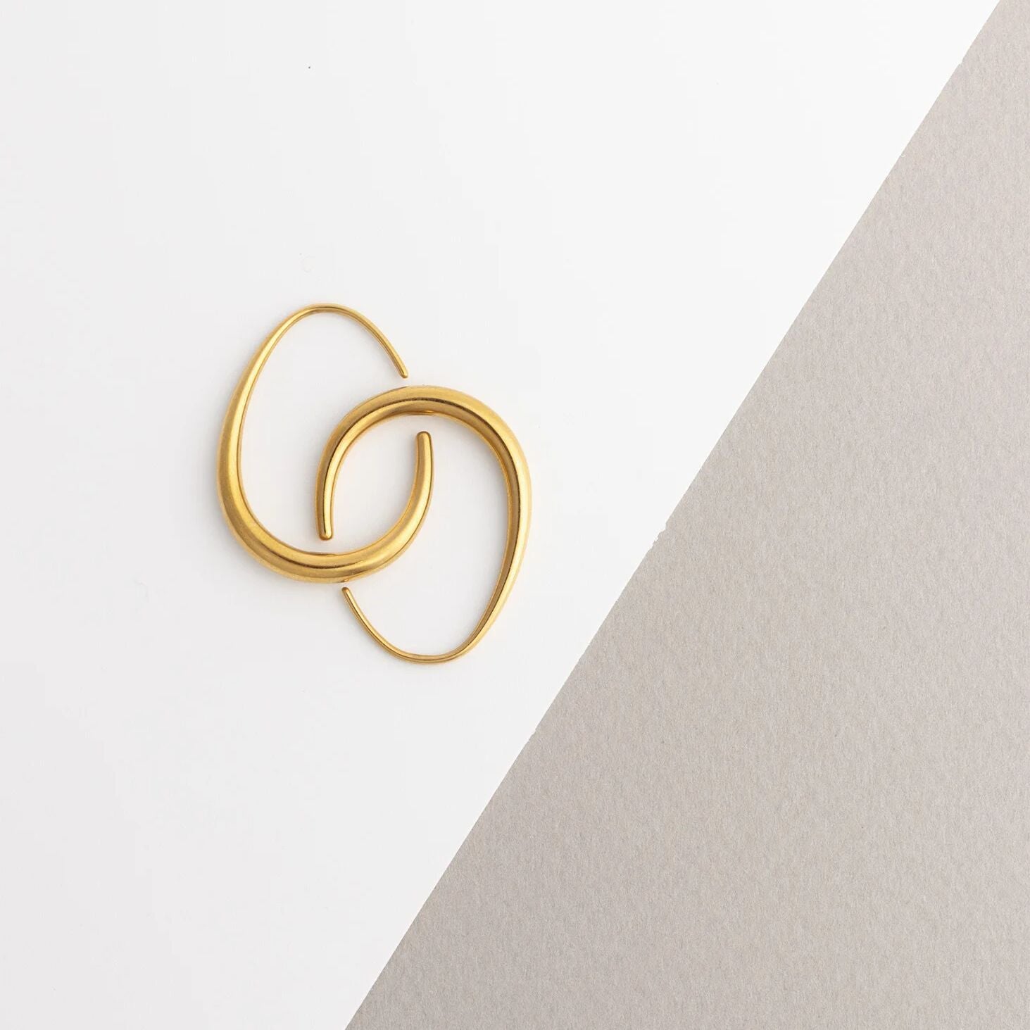 Gold hoop earrings on a light gray background