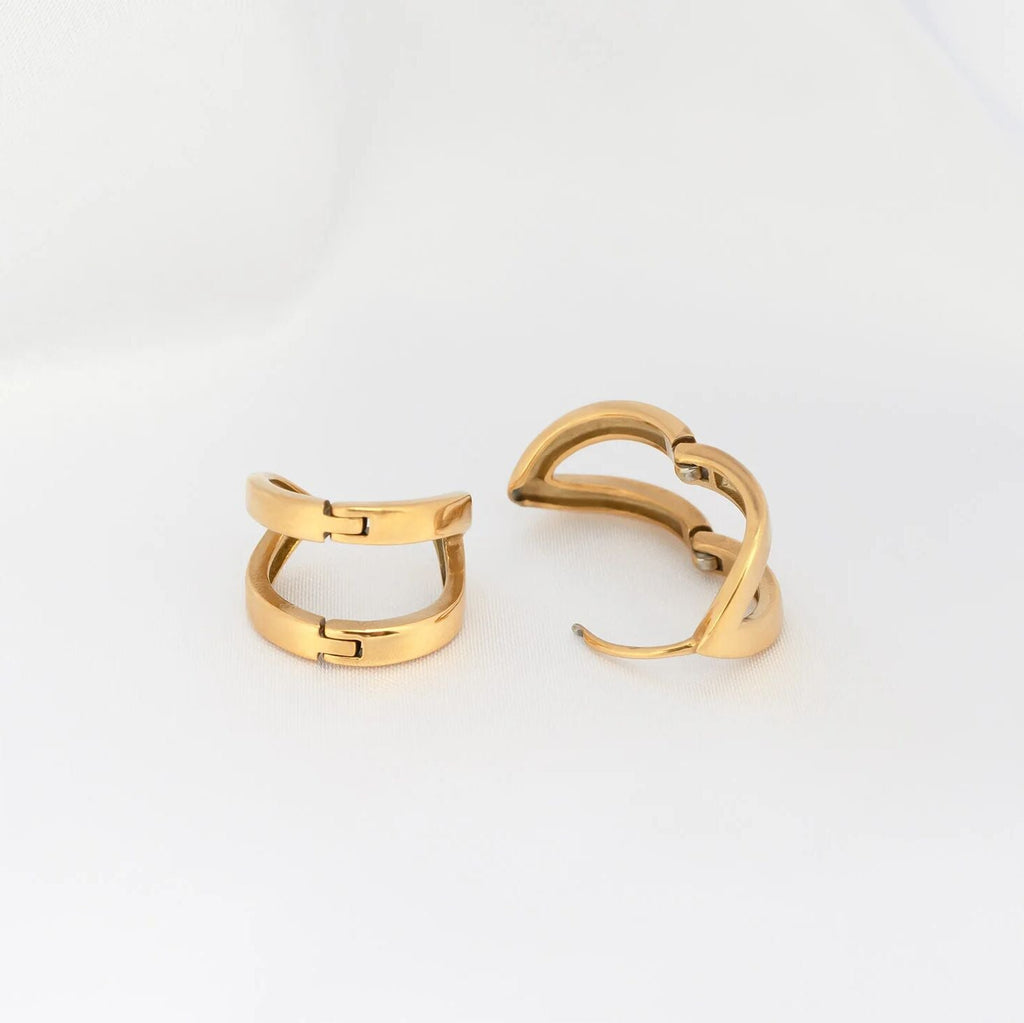 Two gold hoop earrings on a light gray background