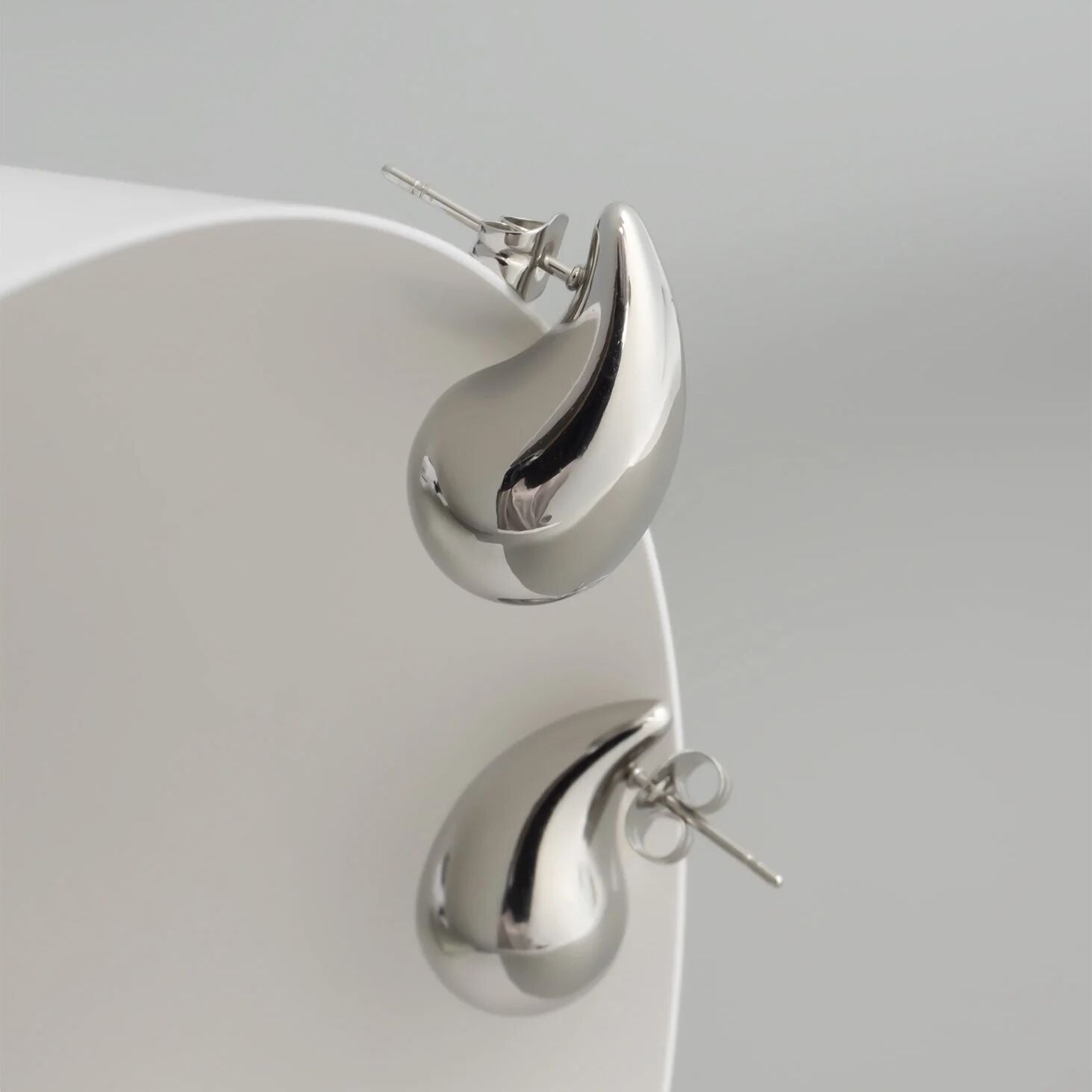 Silver teardrop earrings on a light gray background