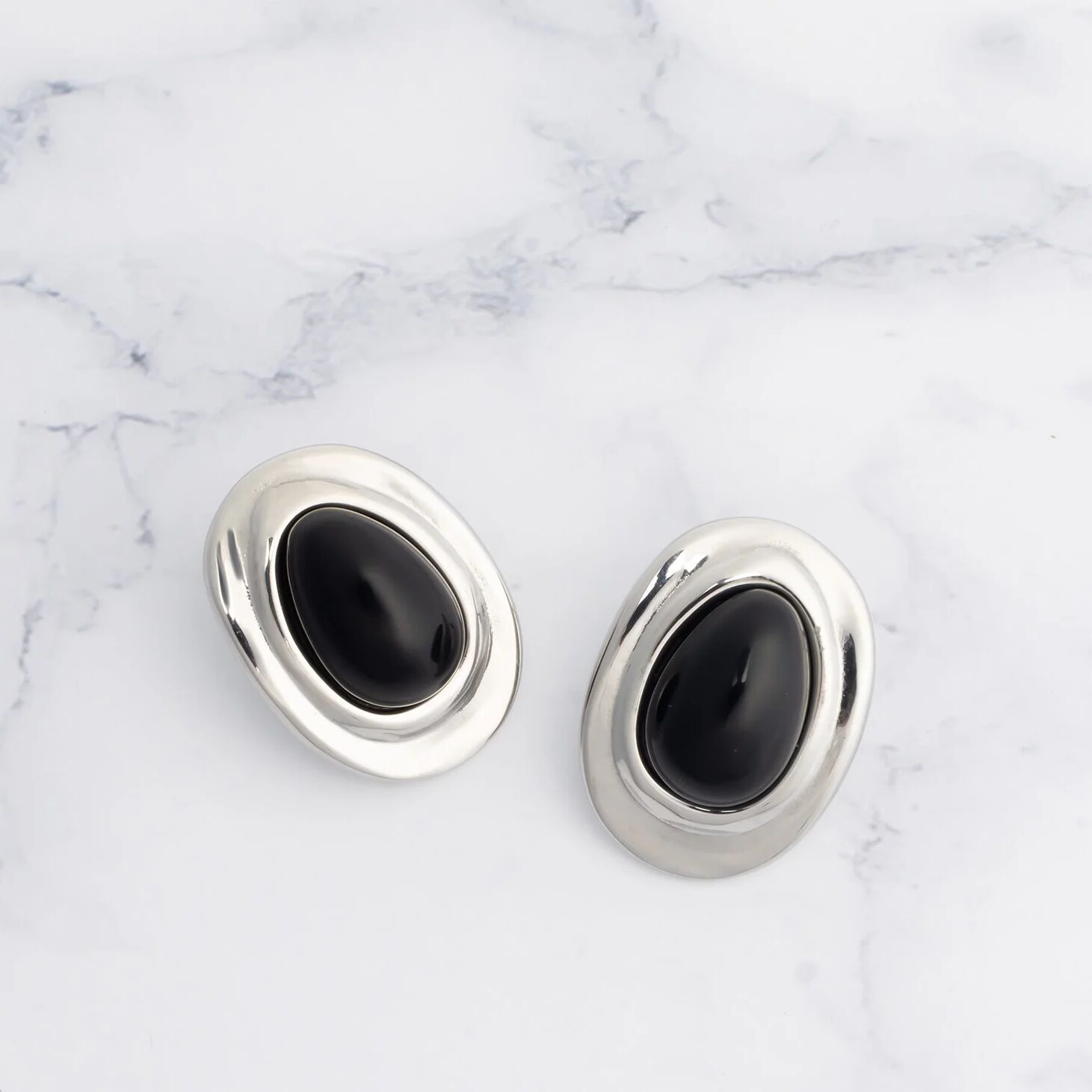 Pair of silver Black Enamel Stud Earrings on a marble background
