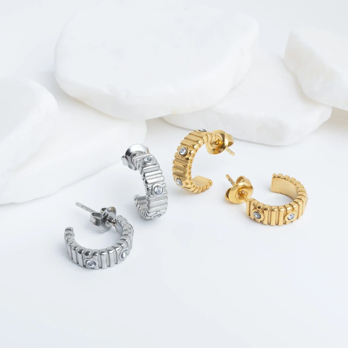 Set of gold and silver hoop Fluted Huggie with Stones Earrings on a white background