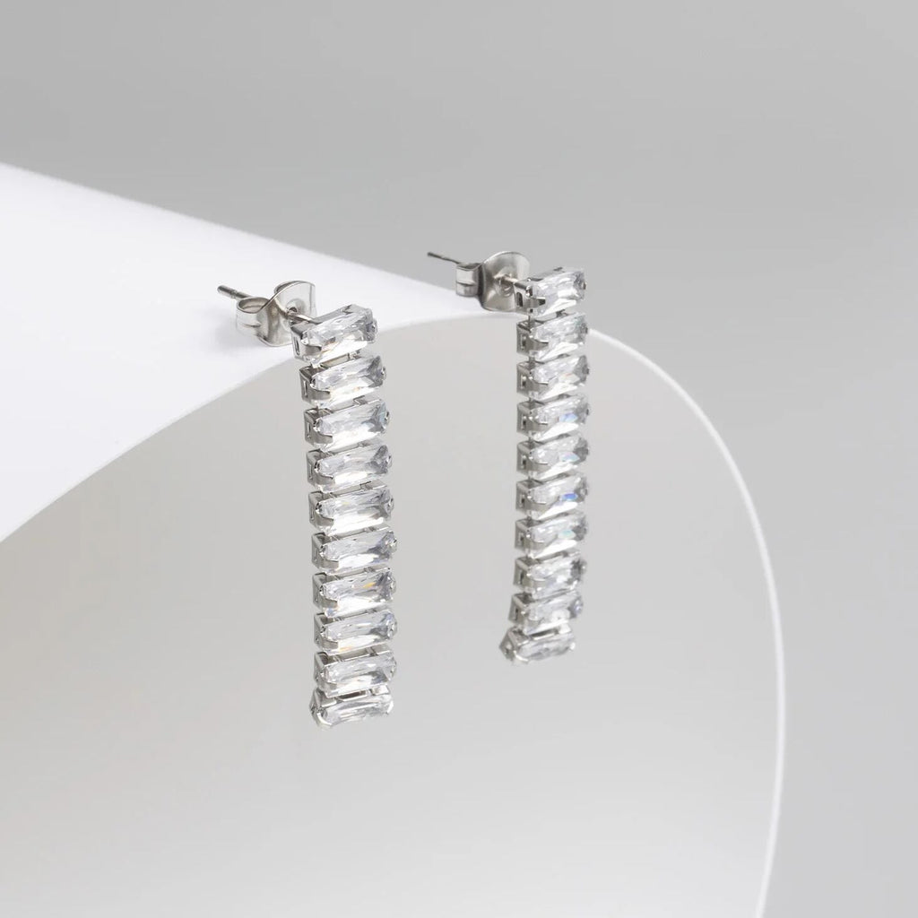 Silver hoop earrings with clear gemstones on a white background