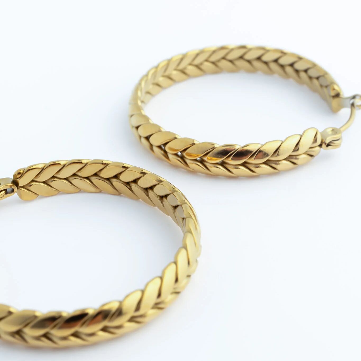 Pair of gold Braided Hoop Earrings on a white background
