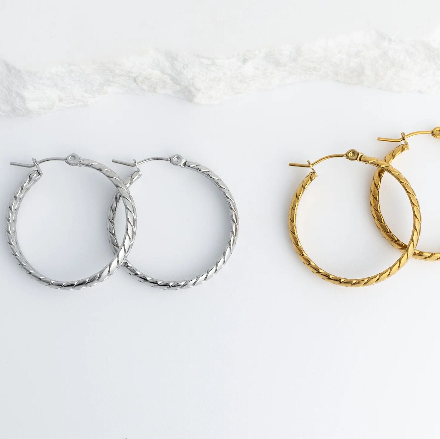 Pair of silver and gold Braided Hoop Earrings on a white background