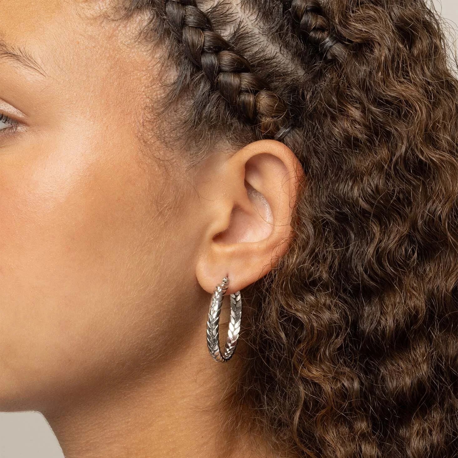 Close-up of an ear with braided hair and silver Braided Hoop Earrings.