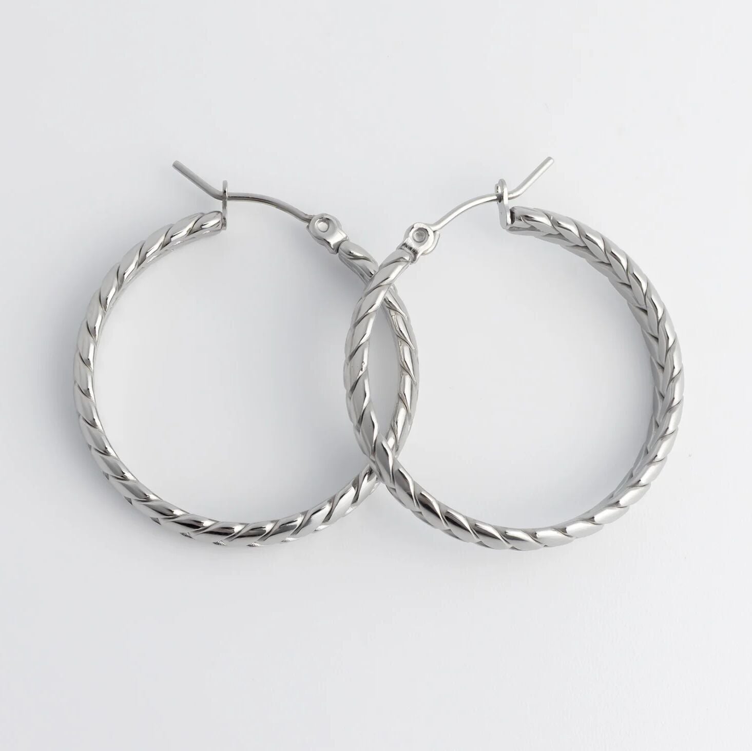 Pair of silver Braided Hoop Earrings on a white background