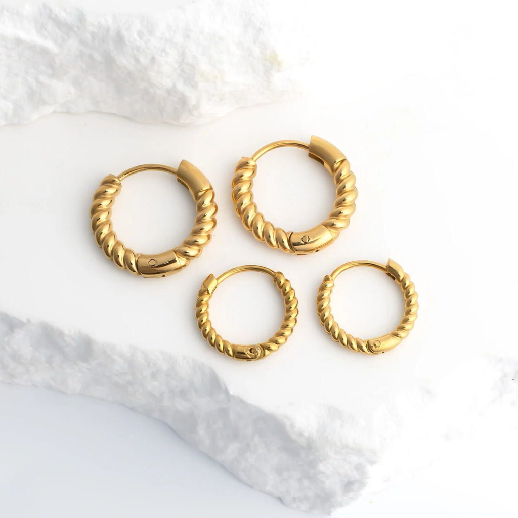 Set of gold hoop earrings on a white marble surface