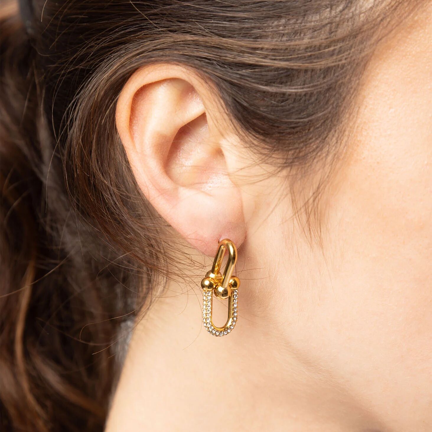 Gold hoop earring worn by a person with brown hair.
