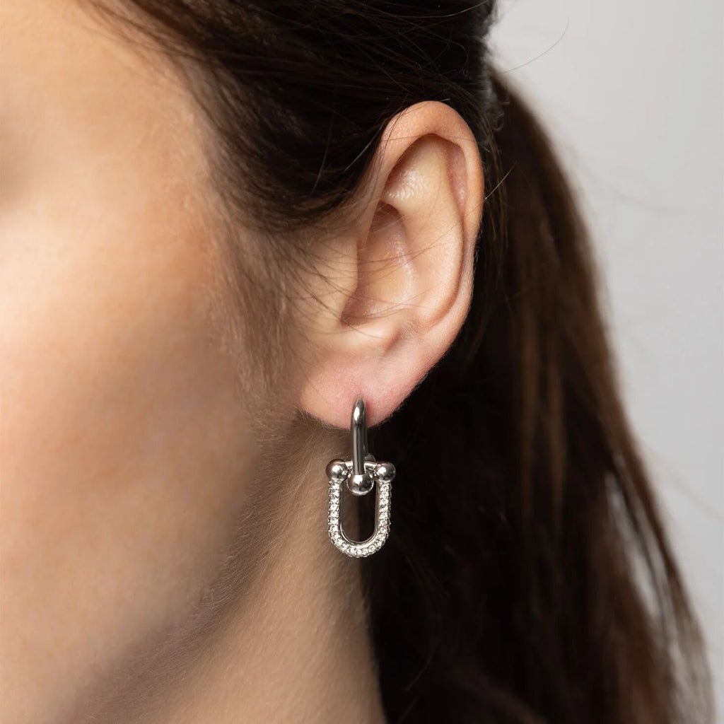 Close-up of an ear wearing a silver hoop earring with a blurred background