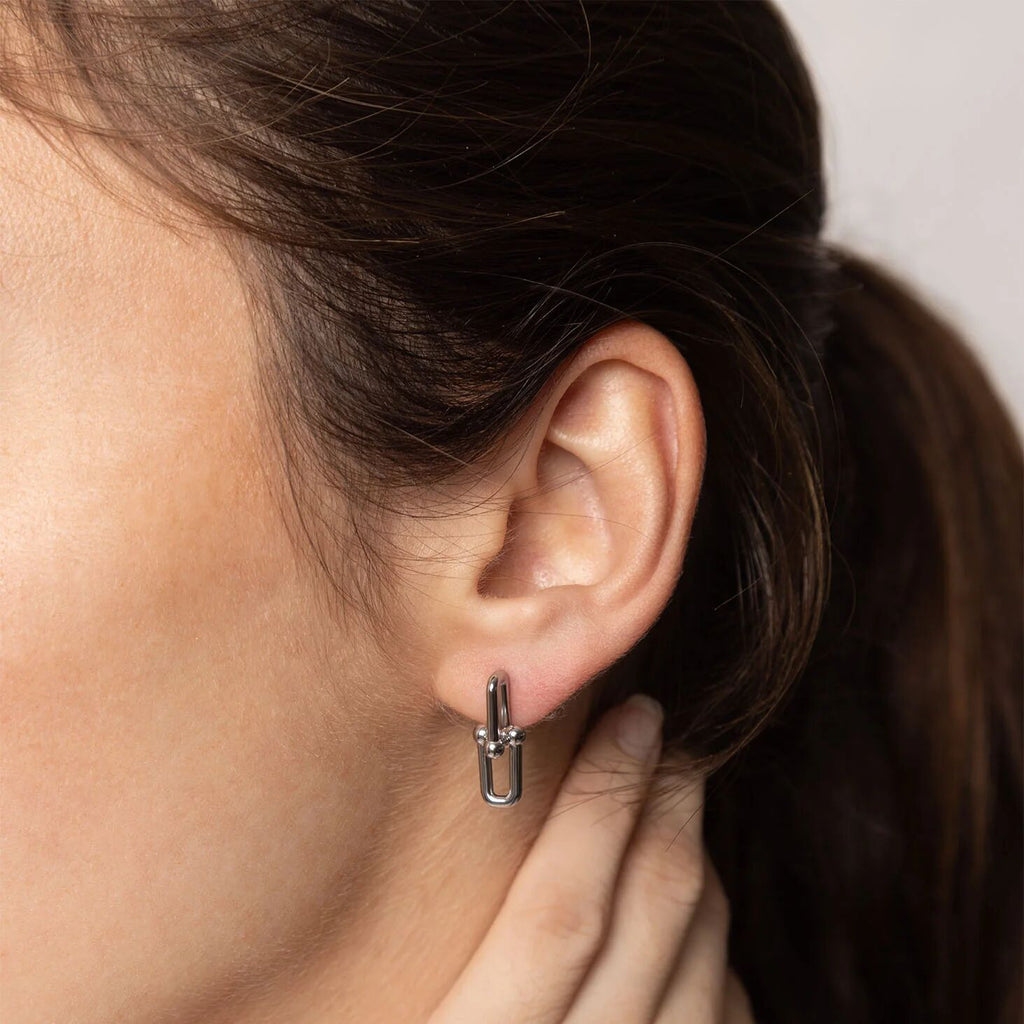 Close-up of an ear wearing a silver hoop earring with hair partially covering the face.