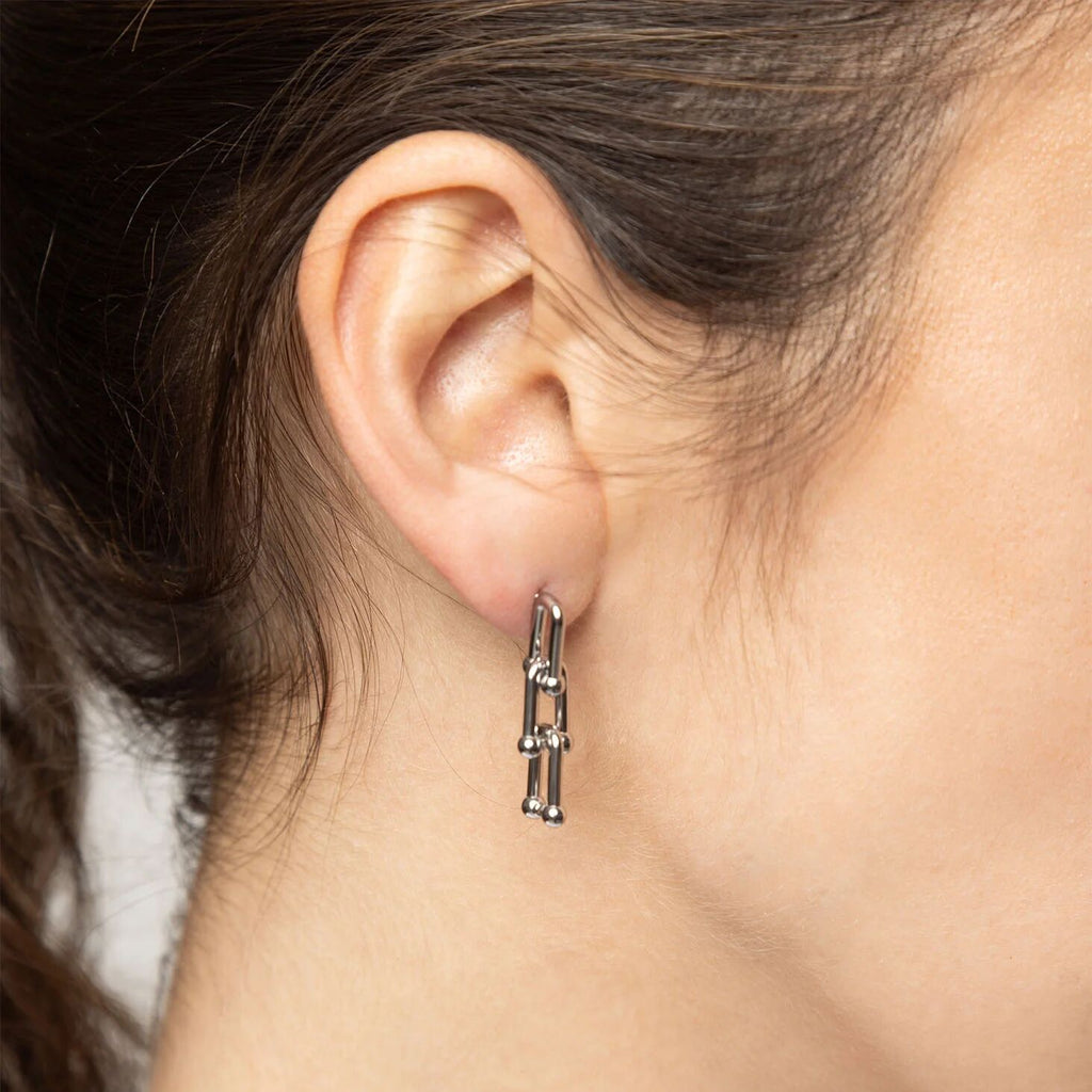 Close-up of an ear wearing a silver earring with a blurred background