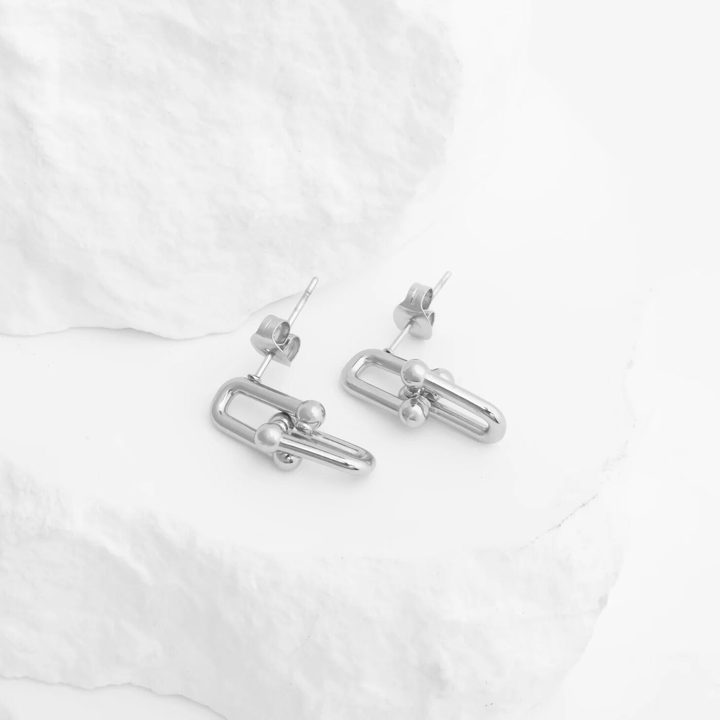 Silver hoop earrings on a white fabric background
