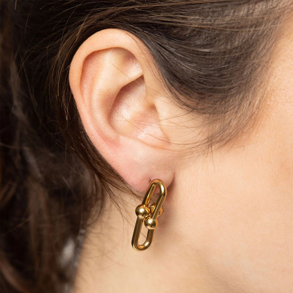 Gold earring worn by a person with dark hair.
