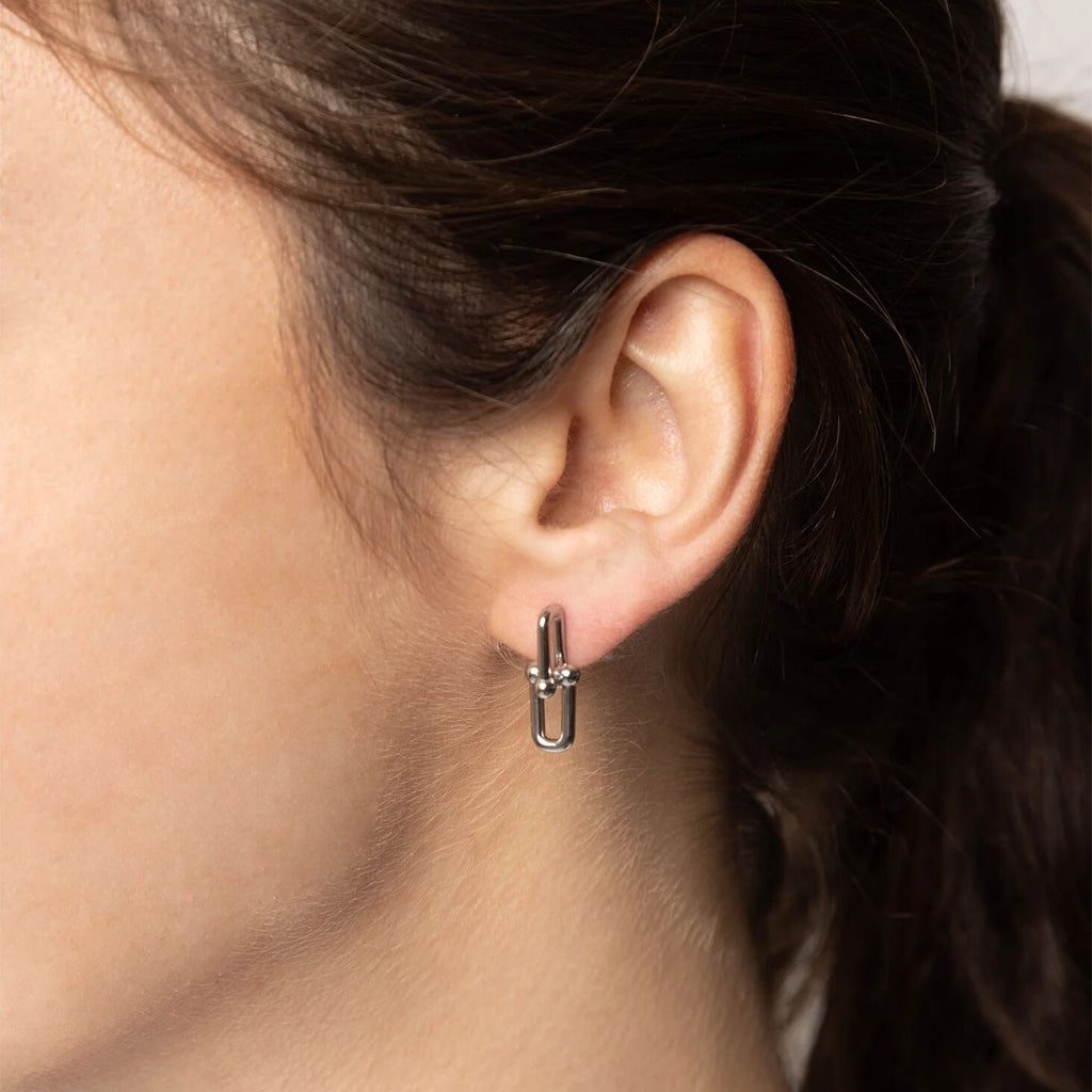 Close-up of an ear wearing a silver hoop earring with dark hair.