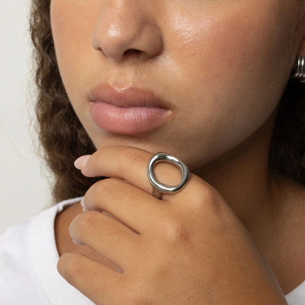 Close-up of a person wearing a silver Oval Motif Ring  on their finger.