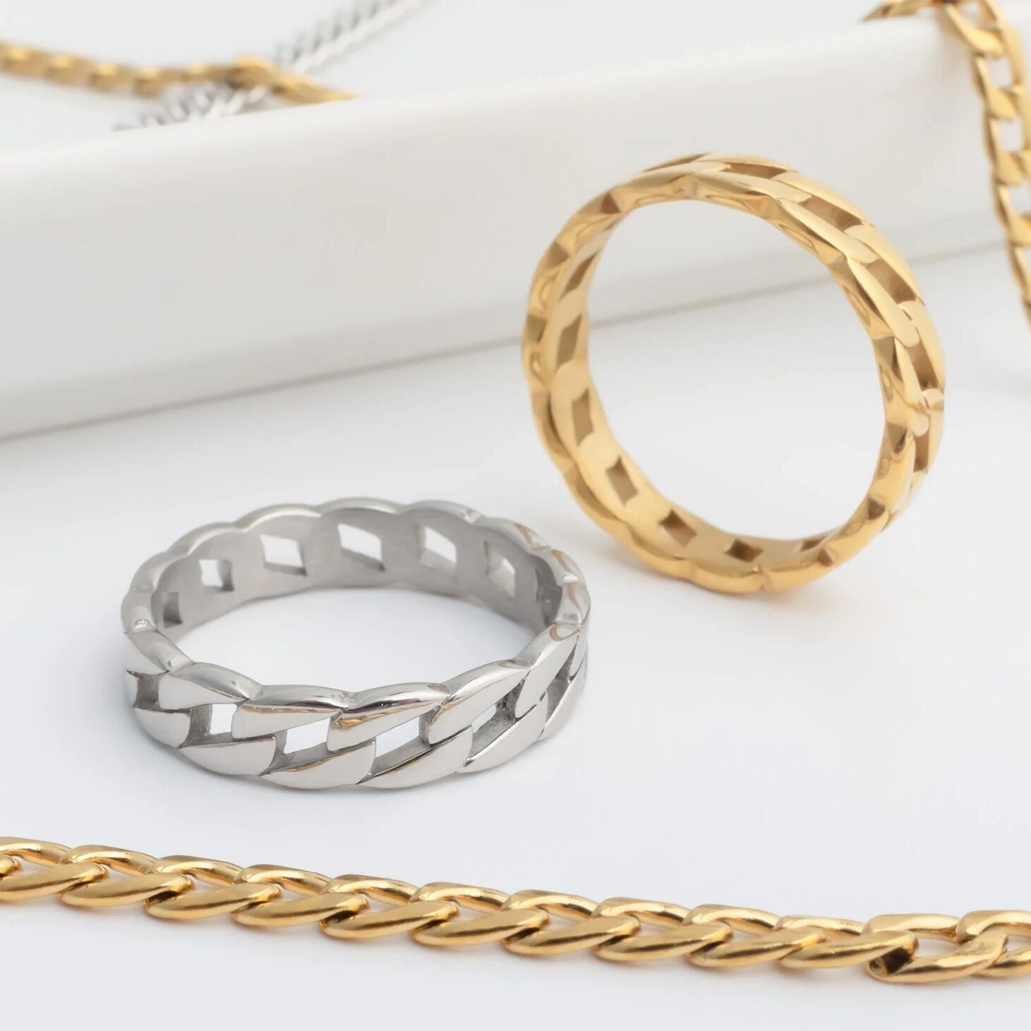 Gold and silver Curb Chain Stacking Rings on a white surface