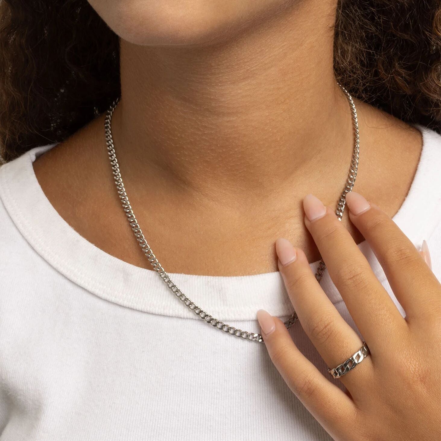 Person wearing a silver necklace and Curb Chain Stacking Ring on a plain background